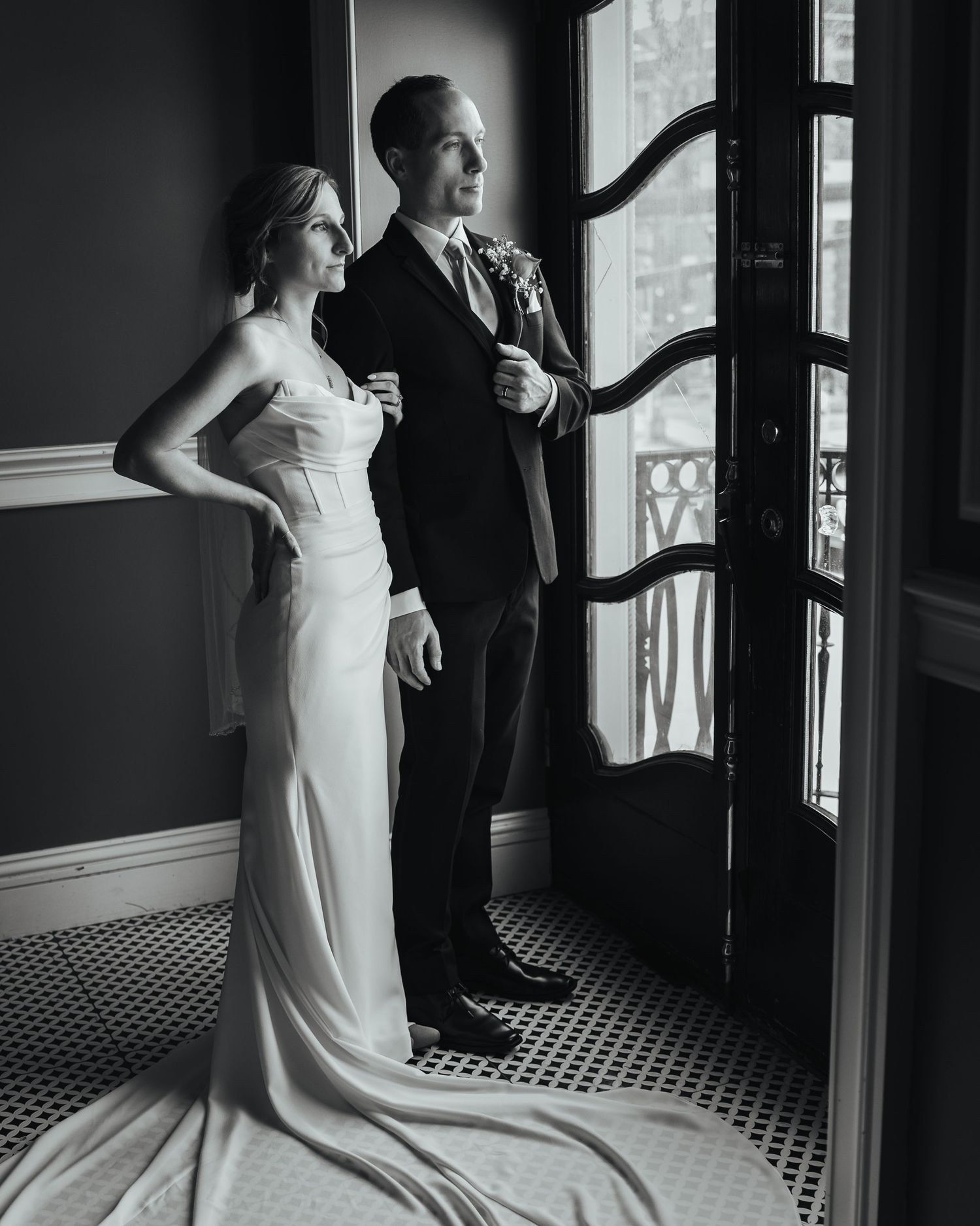 Black and white wedding photos showing couple in elegant poses by window with dramatic lighting and architectural details.
