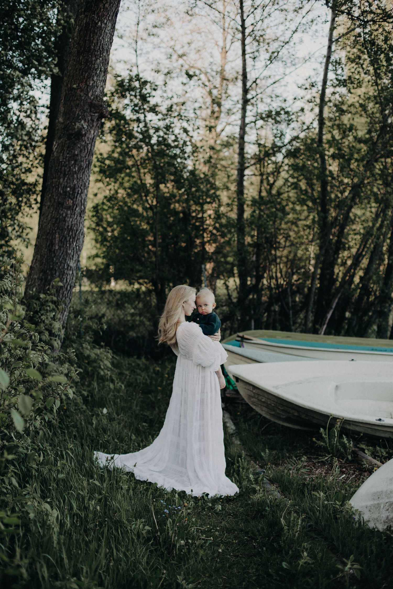 A graceful scene unfolds near boats and trees with flowing white fabric catching the light.