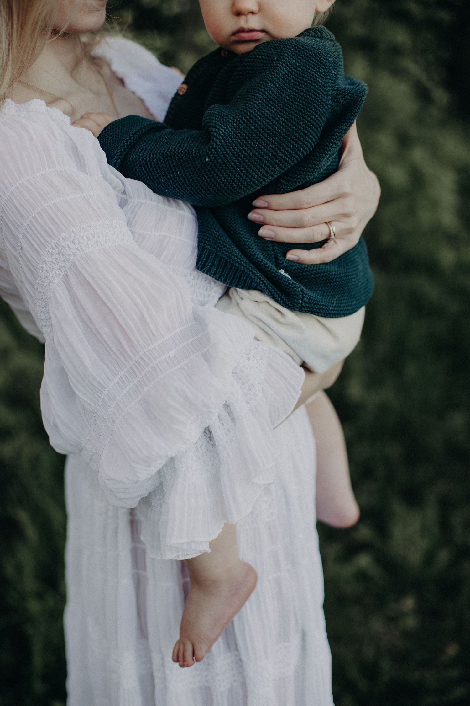 Ethereal outdoor photography featuring white flowing dress and dark sweater in soft lighting.