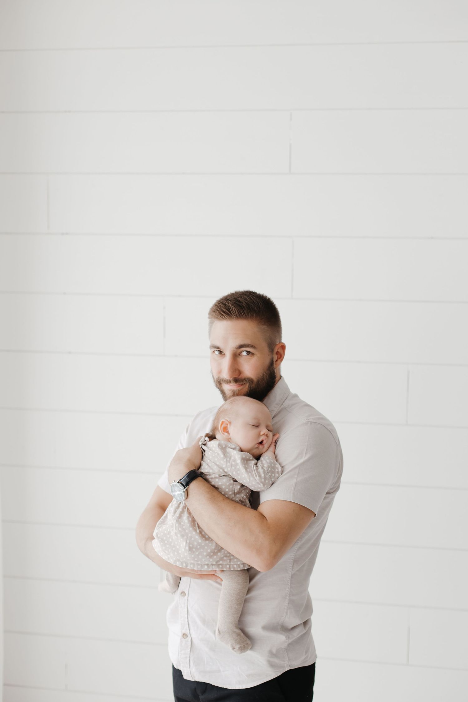 Intimate family moment captured in a bright white studio setting with neutral tones.
