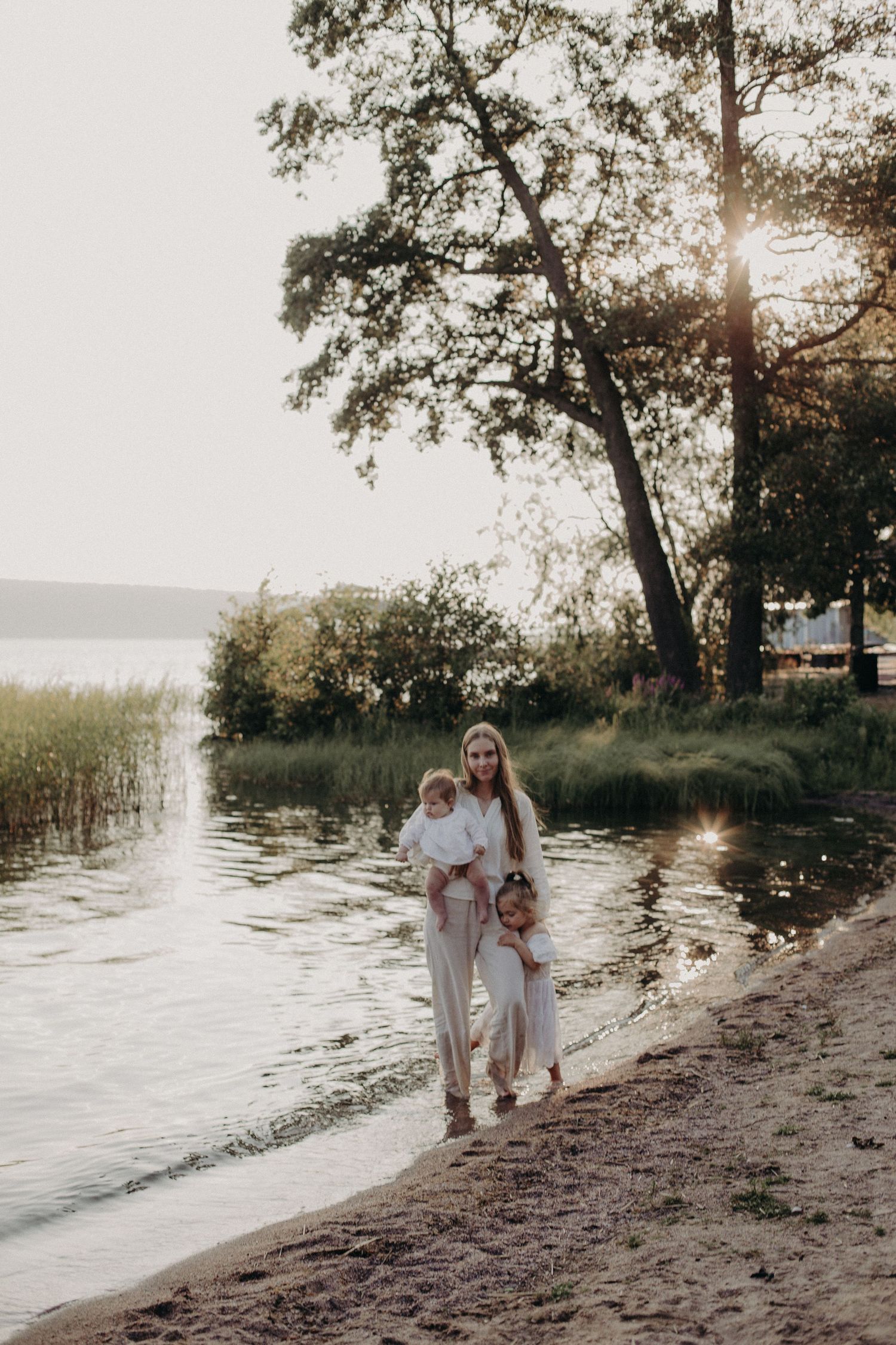 A gentle stroll along the water's edge with trees and sunlight in the background.