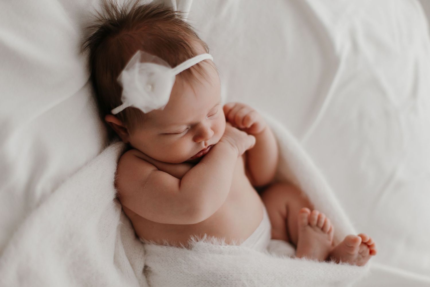 Close-up of sleeping newborn baby in soft natural lighting.