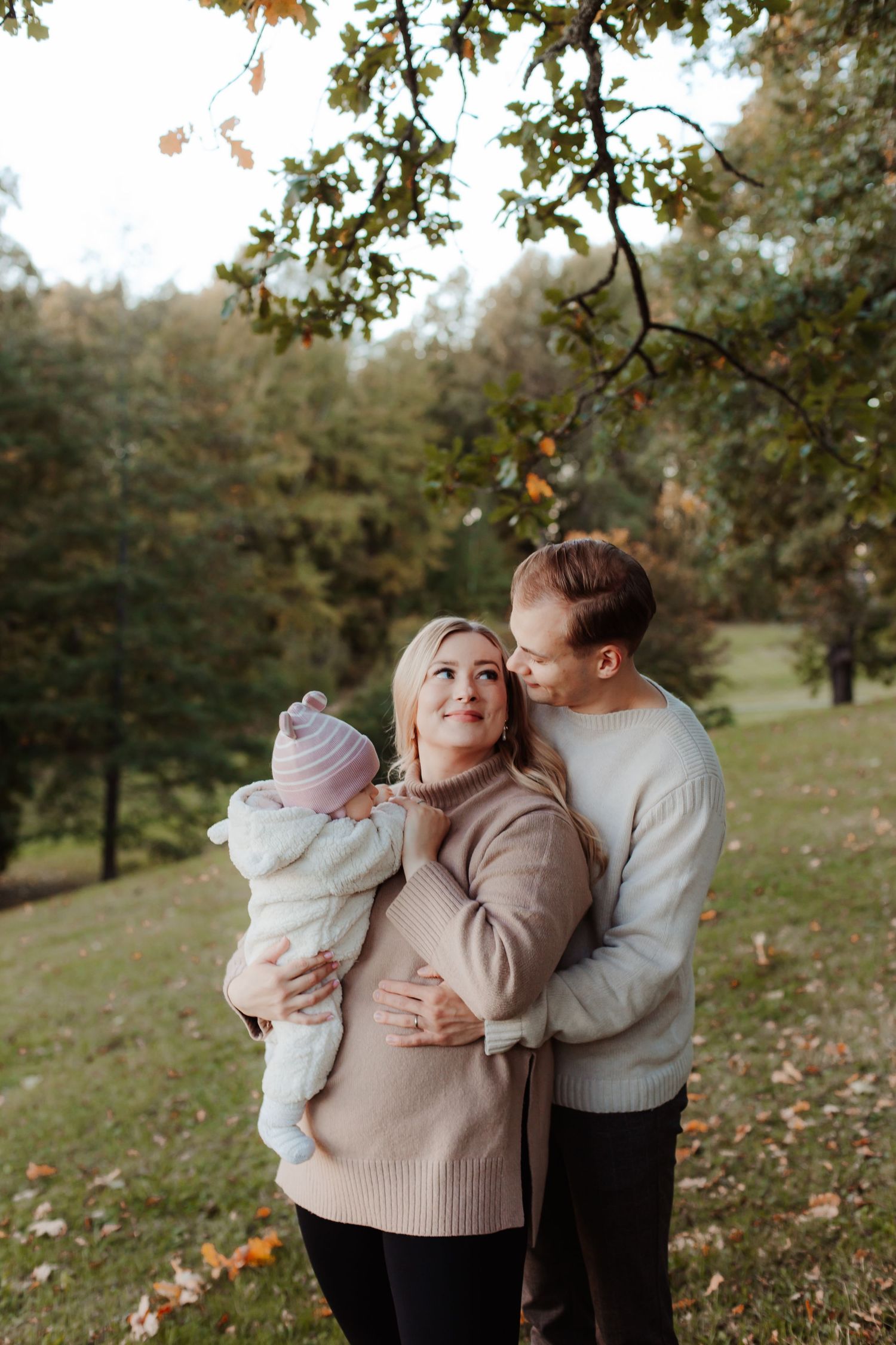 Family embracing outdoors in an autumn orchard setting.