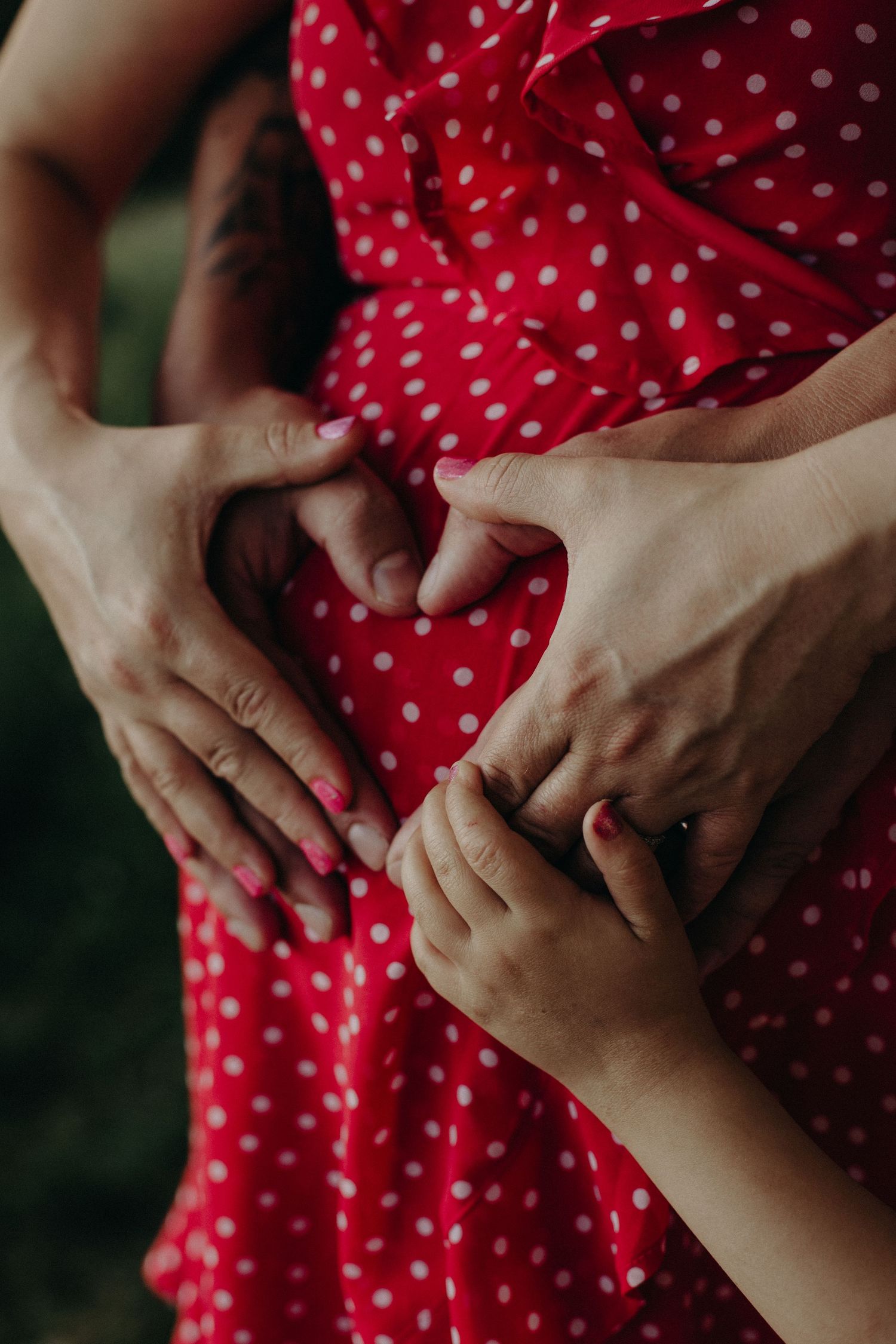 Close-up detail of hands on a red polka dot dress in natural lighting.