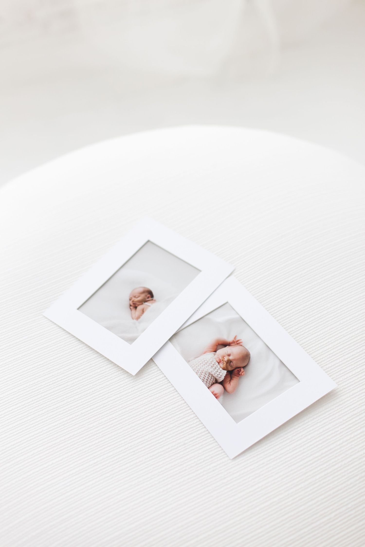 Minimalist white paper photo frame mockups arranged on a light wooden surface with soft shadows.