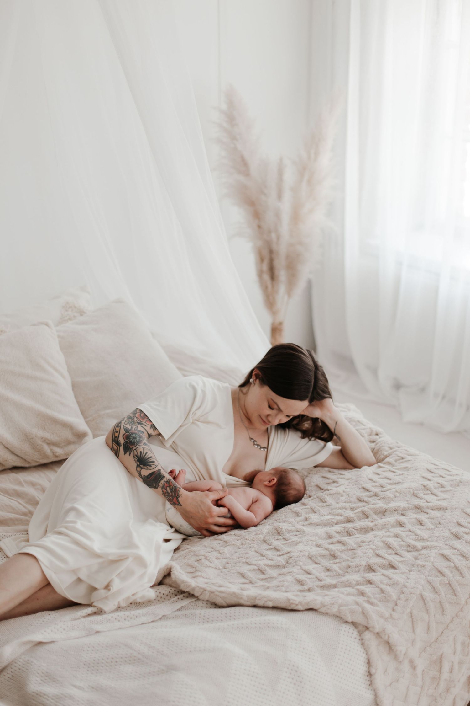 Mother and baby sharing tender moment on white quilted bedding.
