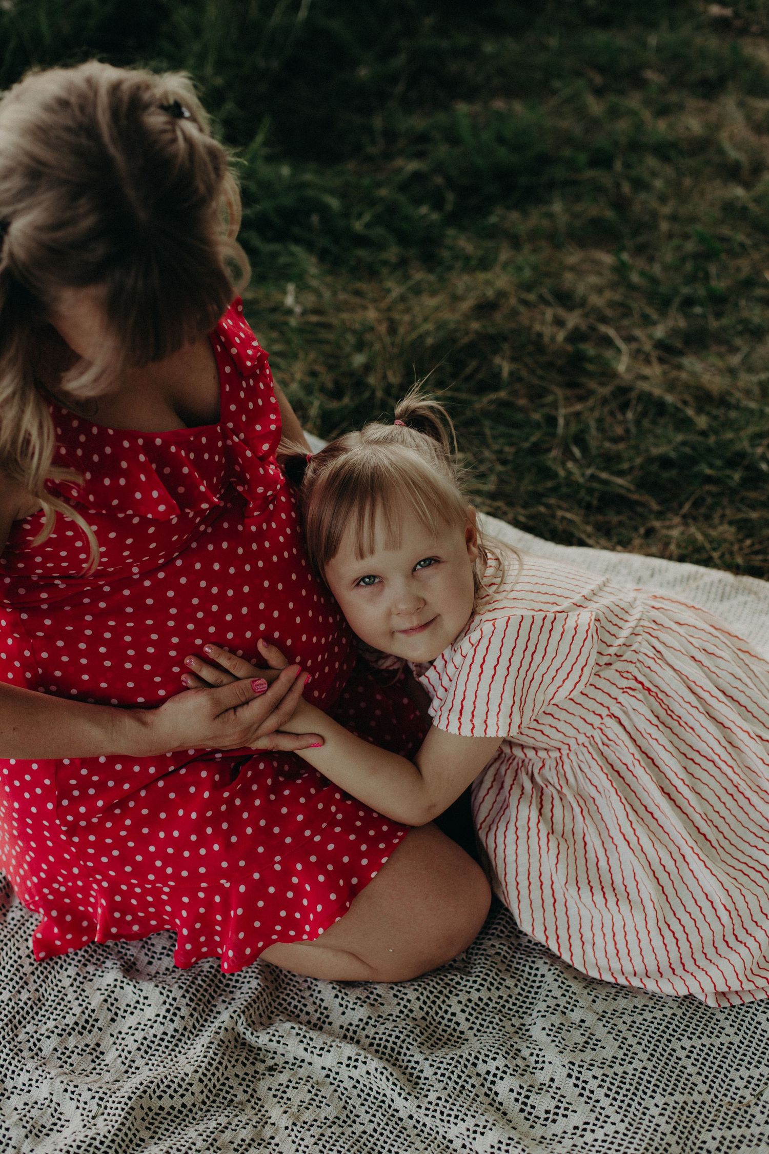 A sweet moment captured between parent and child lying on a lace blanket outdoors.