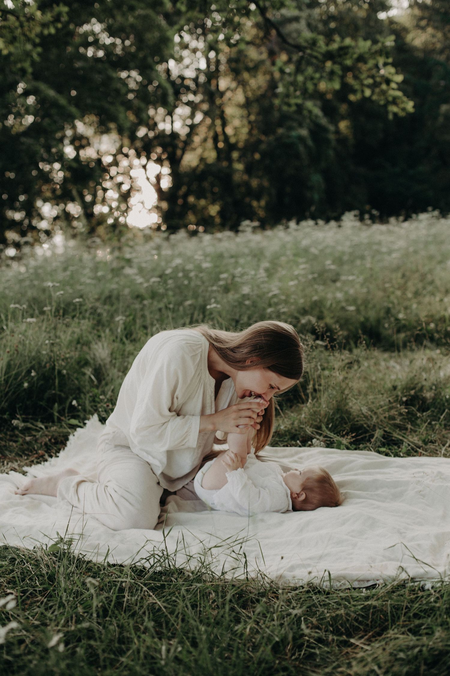 An intimate portrait on a white blanket amidst tall grass and natural surroundings.