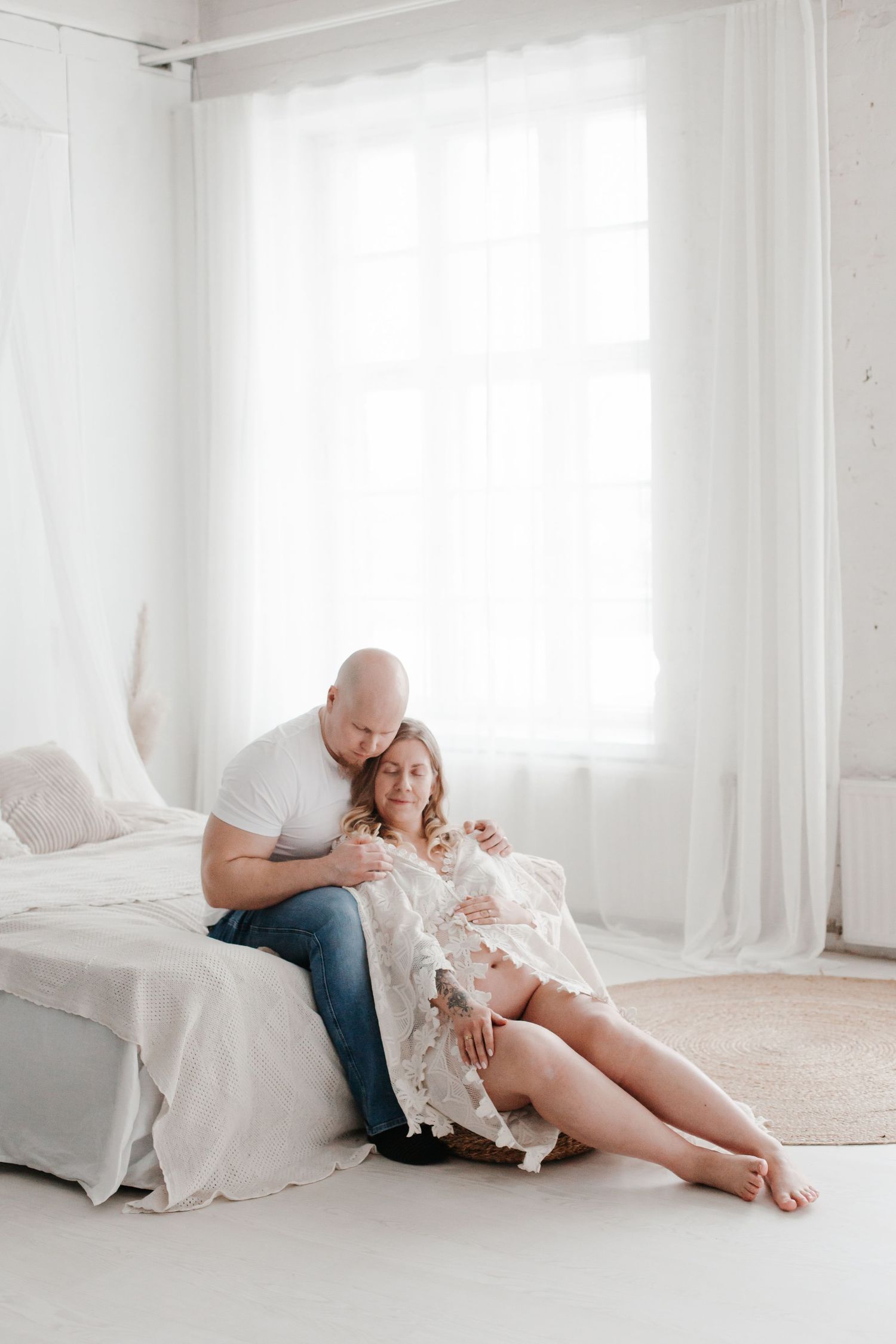 Intimate maternity session in bright white studio with casual styling and natural poses.