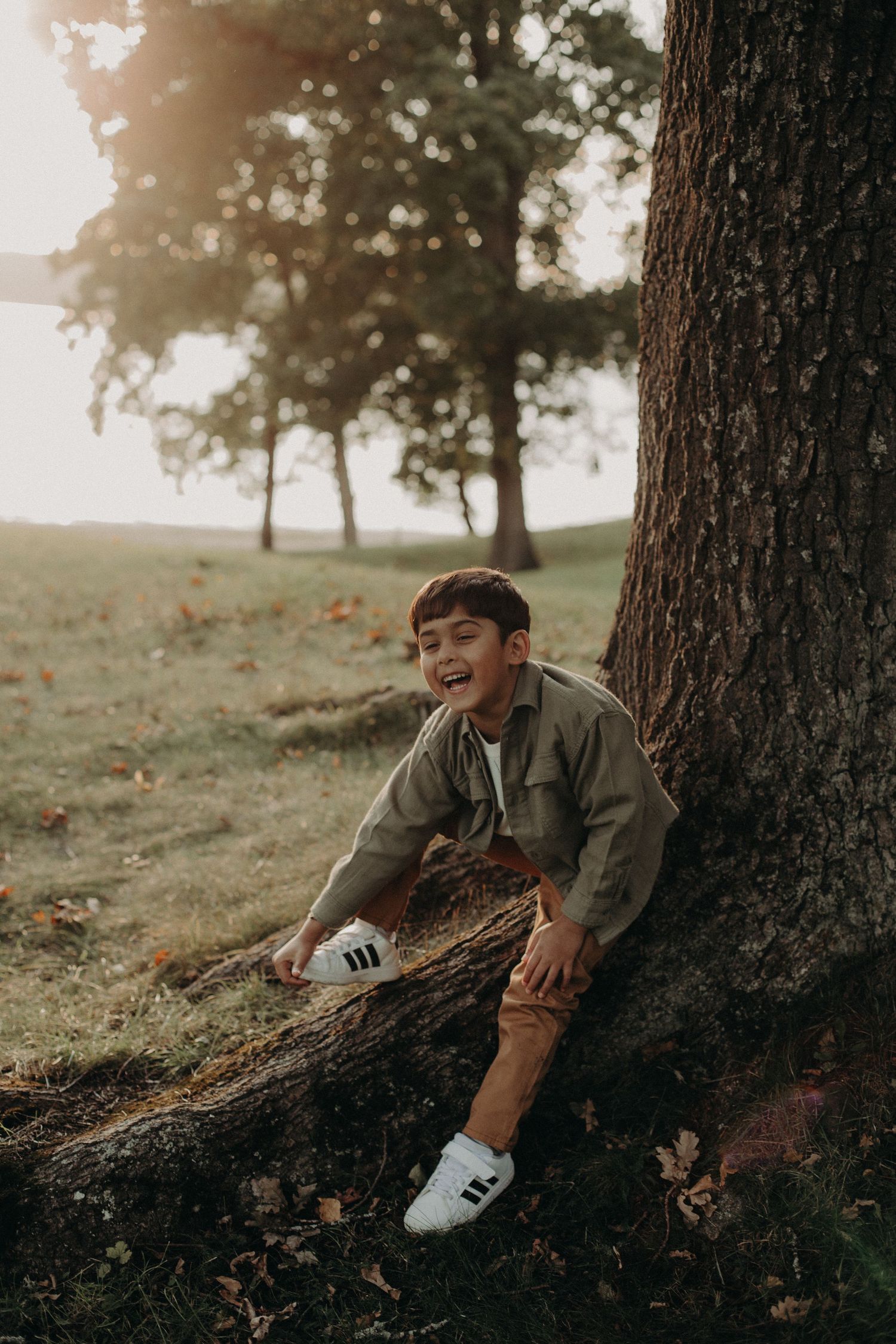 Casual portrait session near tree trunk in park during golden hour.