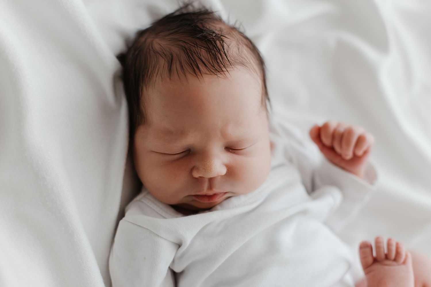 Close-up of sleeping newborn baby in white blanket.