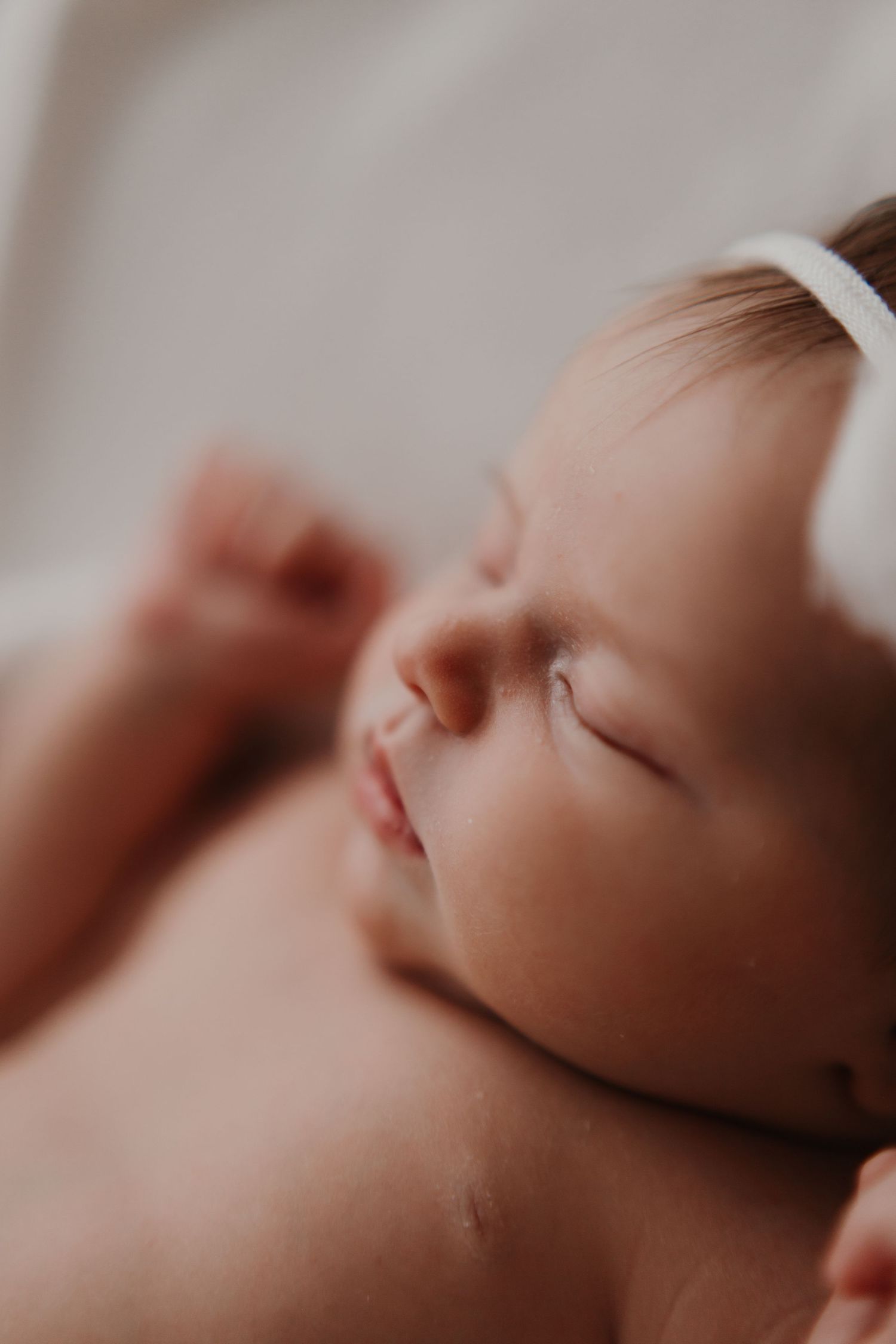 Peaceful macro shot of sleeping newborn's face in gentle lighting.
