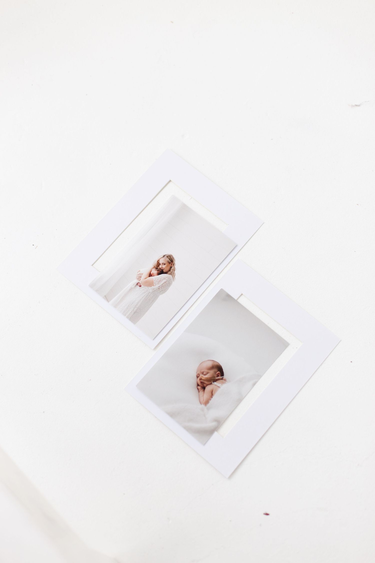 Two minimalist polaroid photographs displayed on a white surface showing artistic portrait poses in soft lighting.
