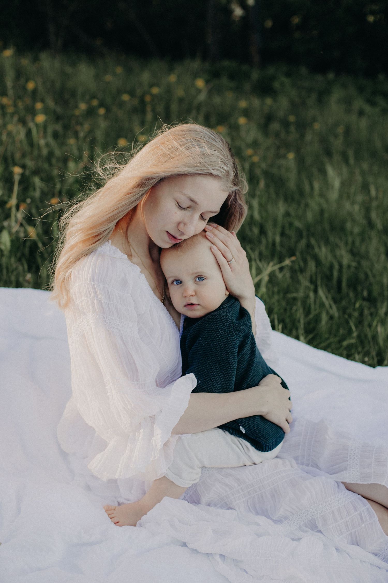 Serene outdoor photography with white dress and navy sweater on grass.