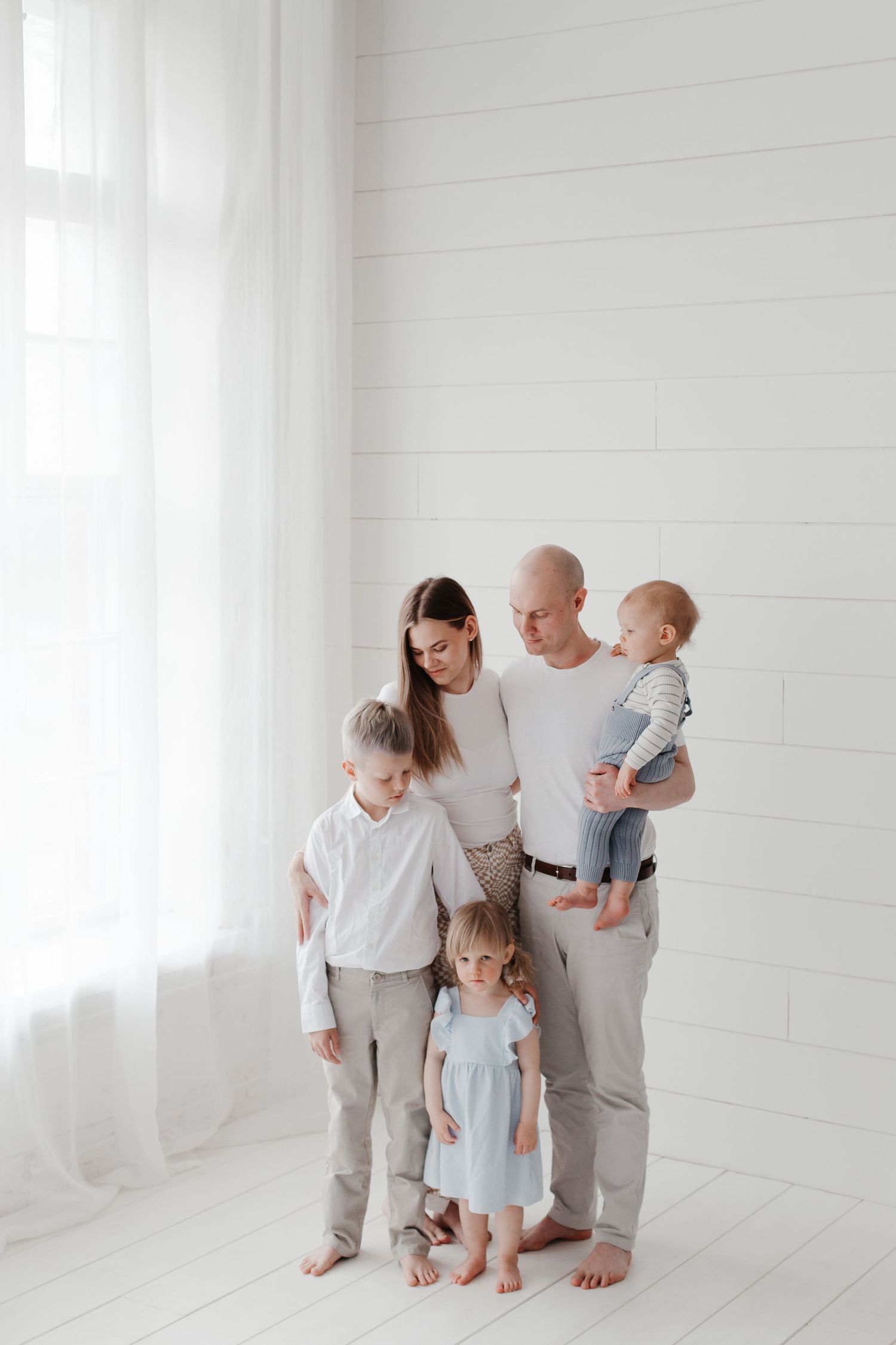 Candid family portrait in soft neutral colors against white background.