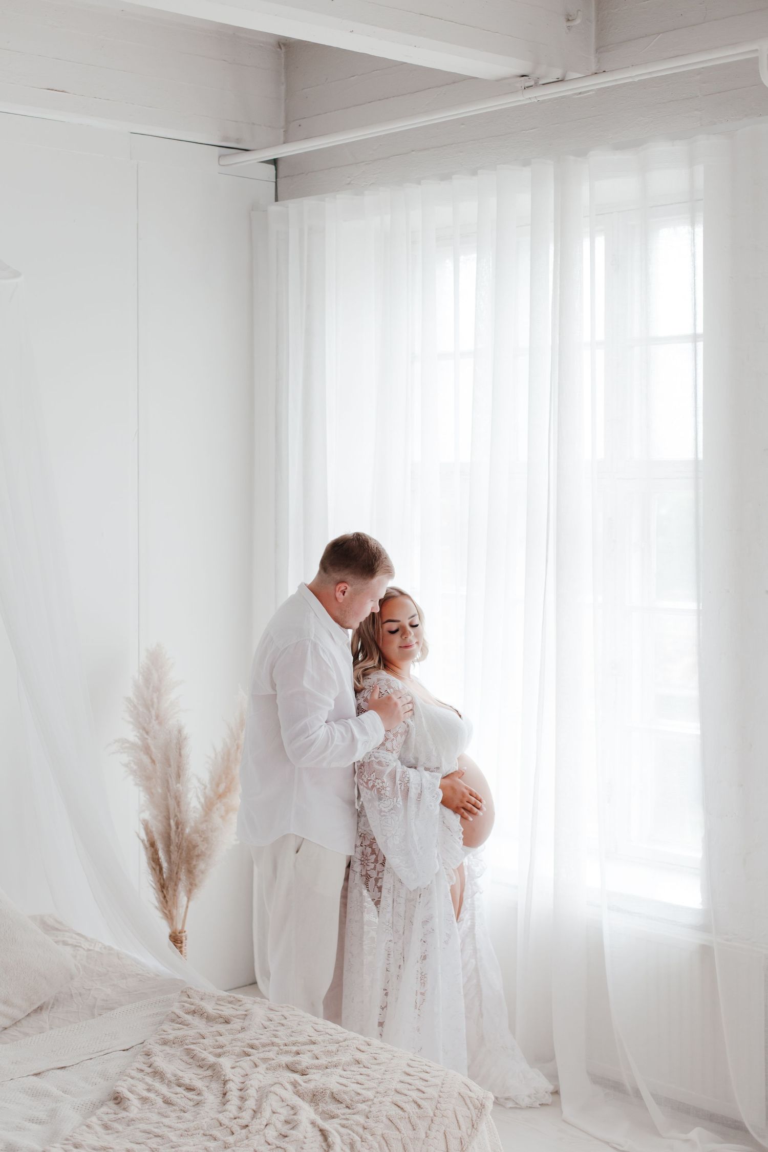 Romantic maternity portraits captured in minimalist white studio setting.