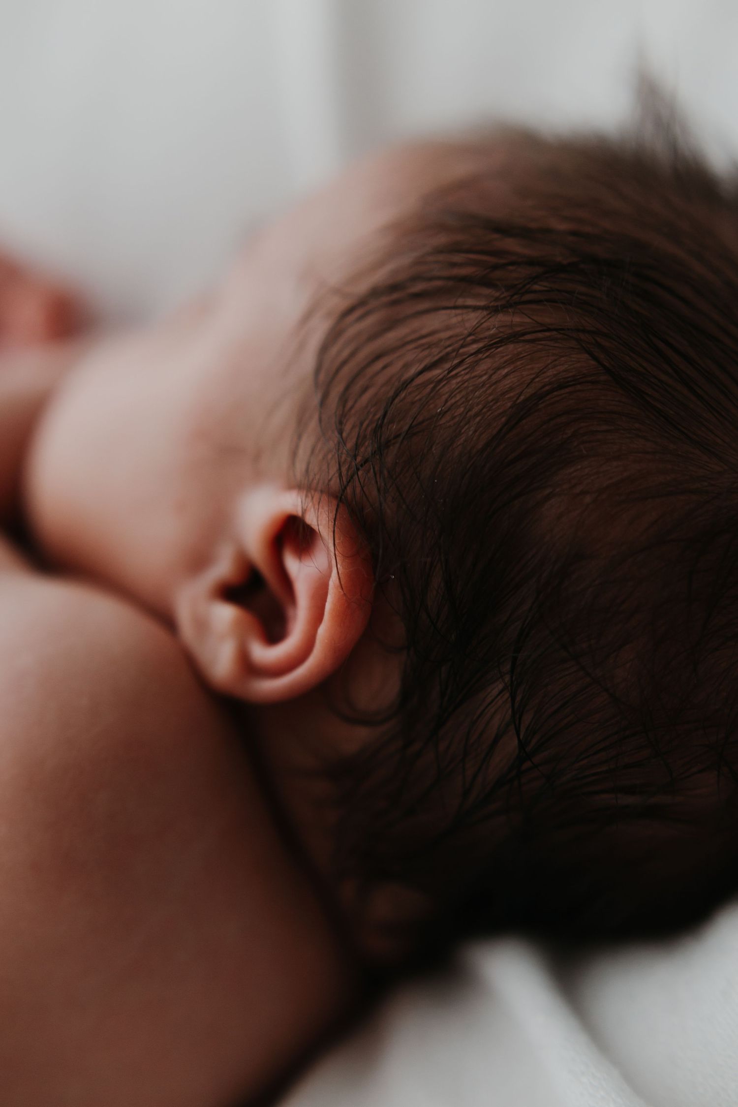 Close-up profile view of sleeping newborn baby with dark hair.