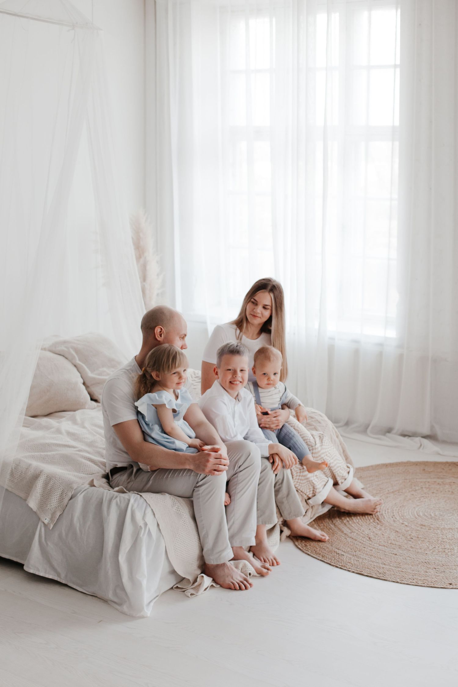Family members sitting together on white couch in bright minimalist living room.