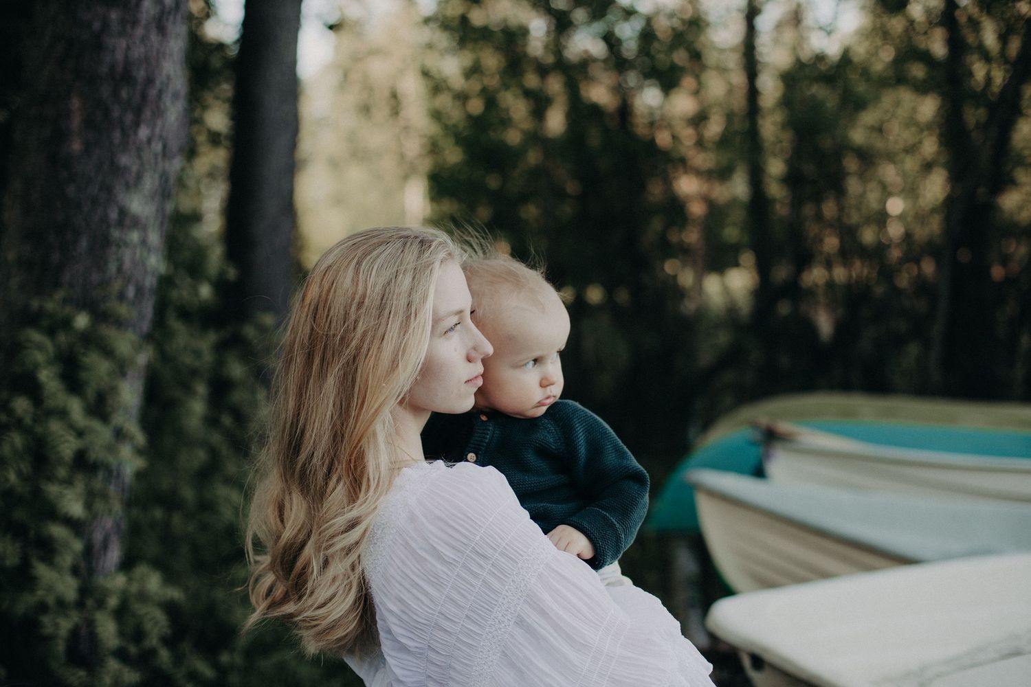 A tender moment captured in nature with boats and trees creating a peaceful backdrop.