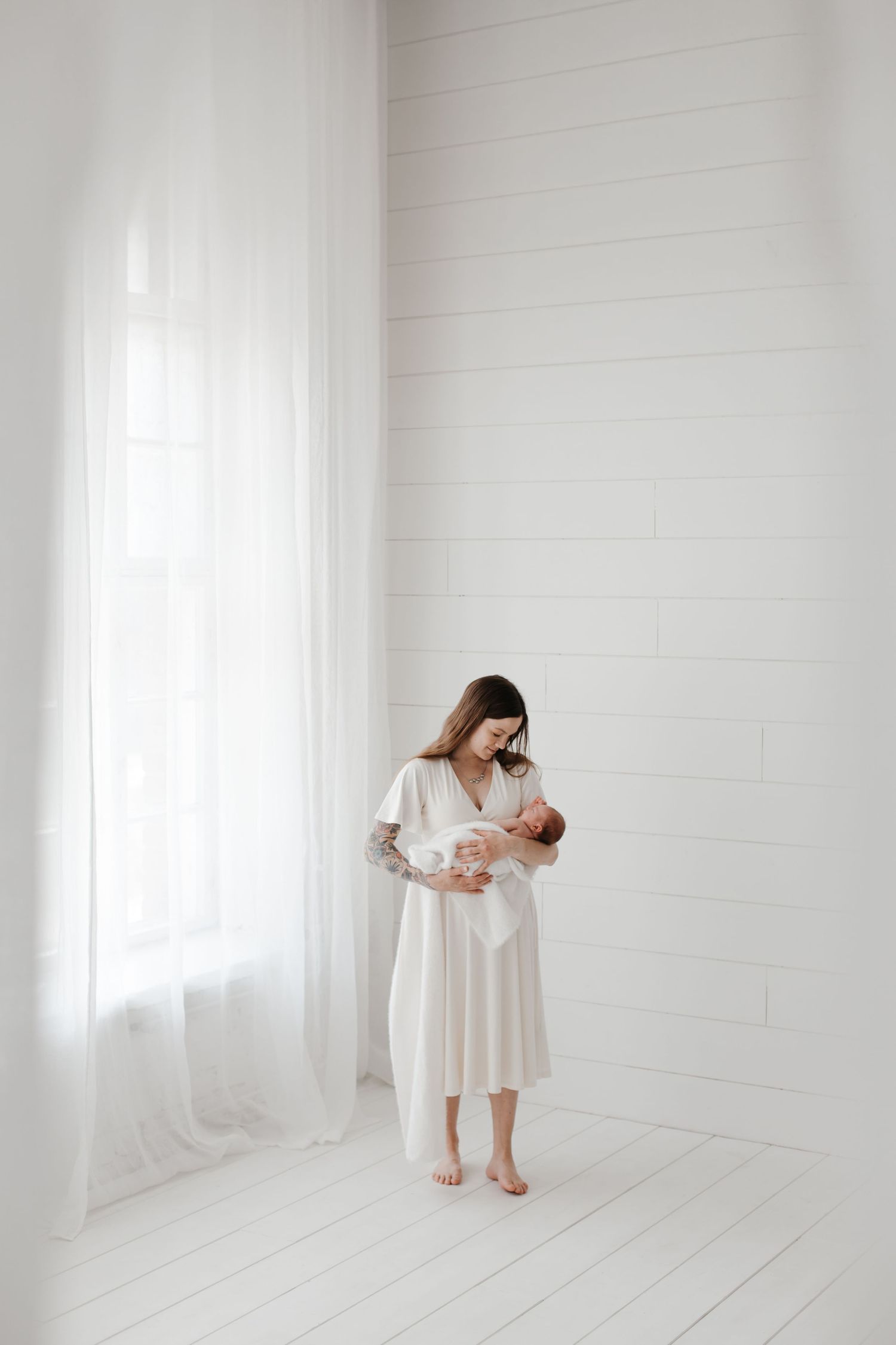 Minimalist white studio setting for newborn photography session.