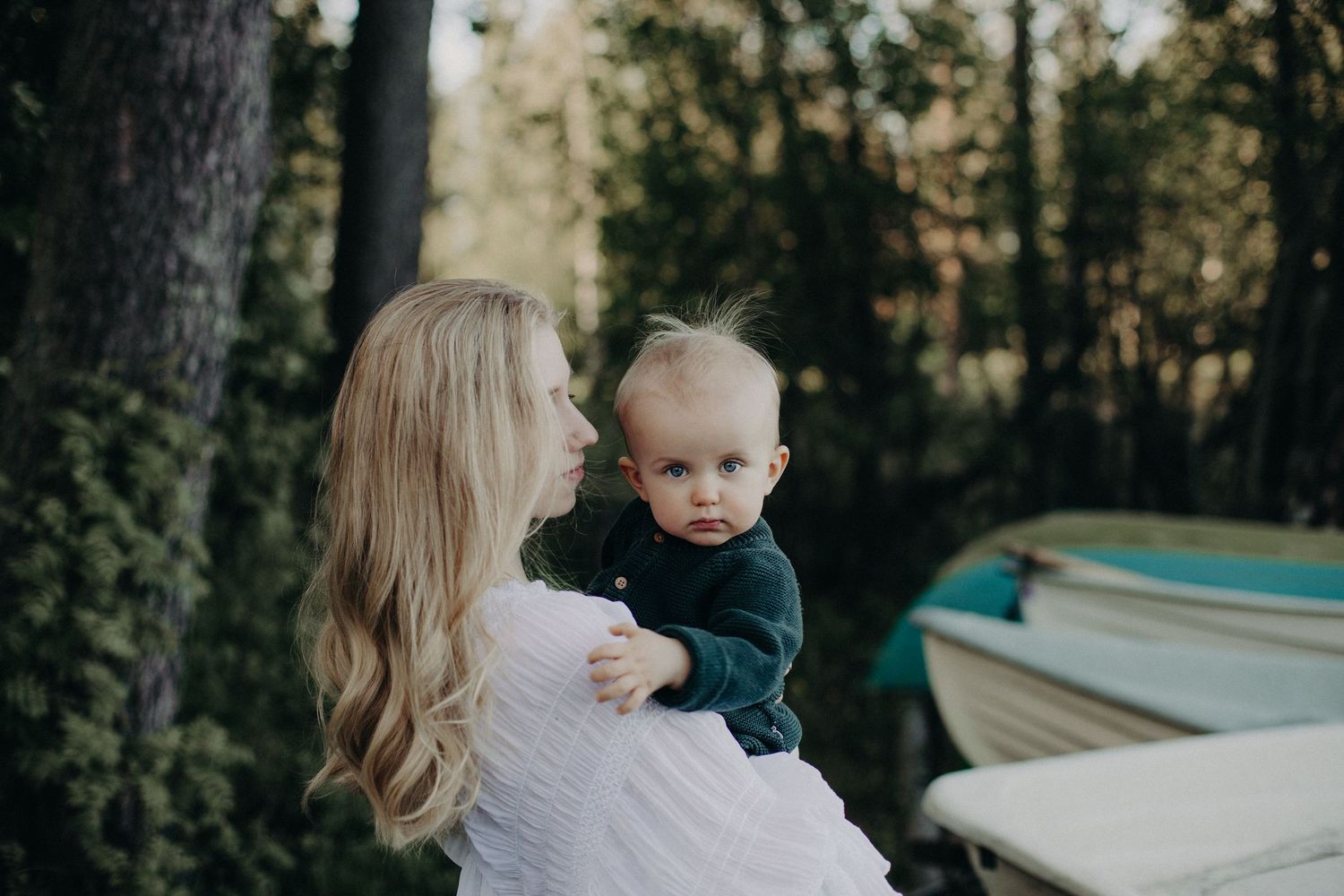 A tender outdoor photoshoot featuring a flowing white dress and navy sweater against a natural backdrop.