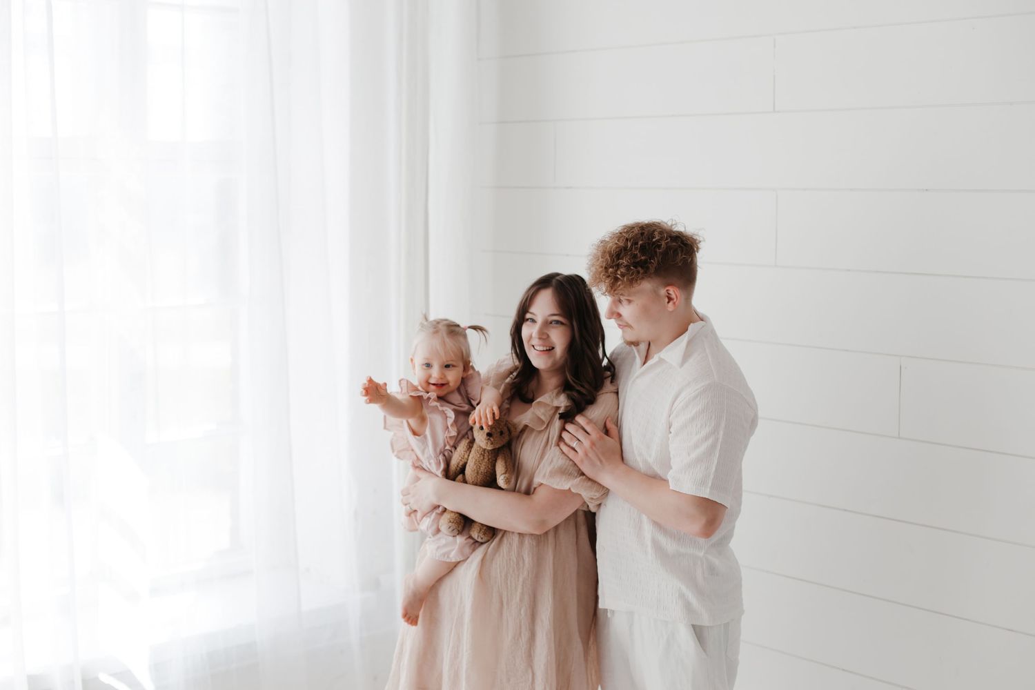 Intimate family moment captured in a bright white room with shiplap walls.