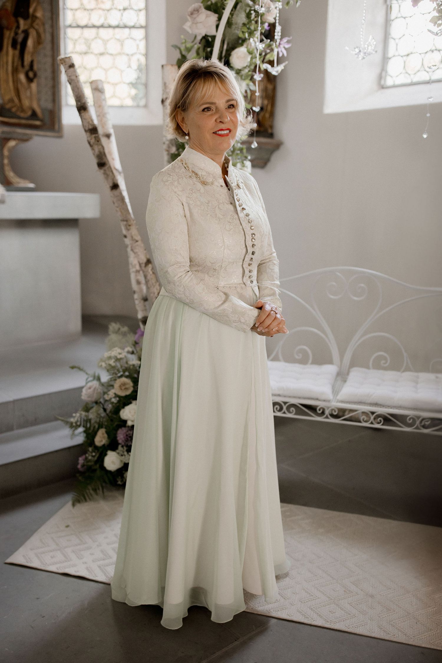 Bride wearing elegant long-sleeve lace bodice wedding dress with mint green skirt, standing in a church.