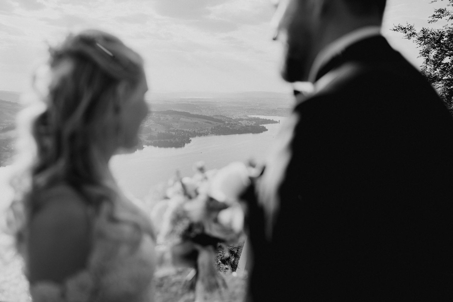 Black and white wedding photo of bride and groom on mountain overlook with scenic river valley backdrop.