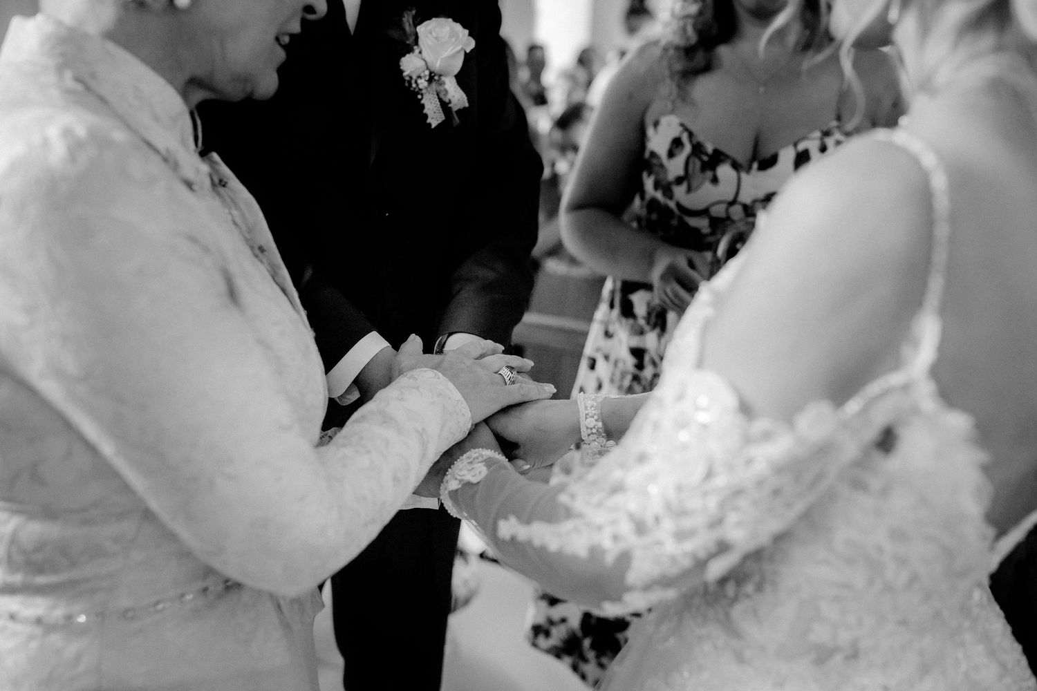 Black and white photo of two brides exchanging rings during a wedding ceremony.