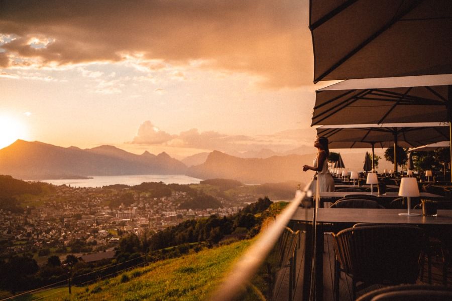 Sunset view over mountain lakes from a terrace restaurant with dramatic orange sky.