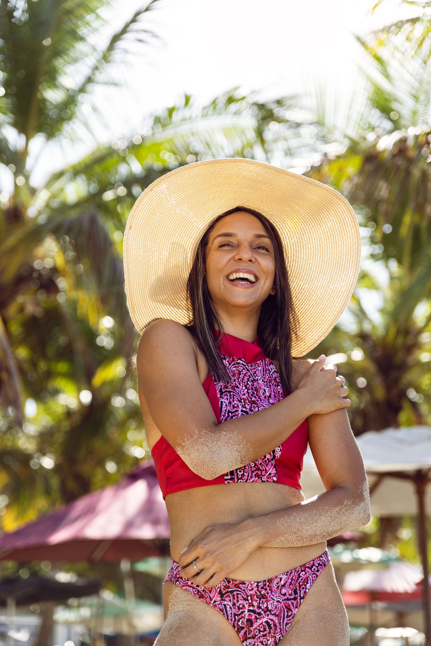 Beachwear photo series with straw hat and pink swimsuit among tropical palm trees.