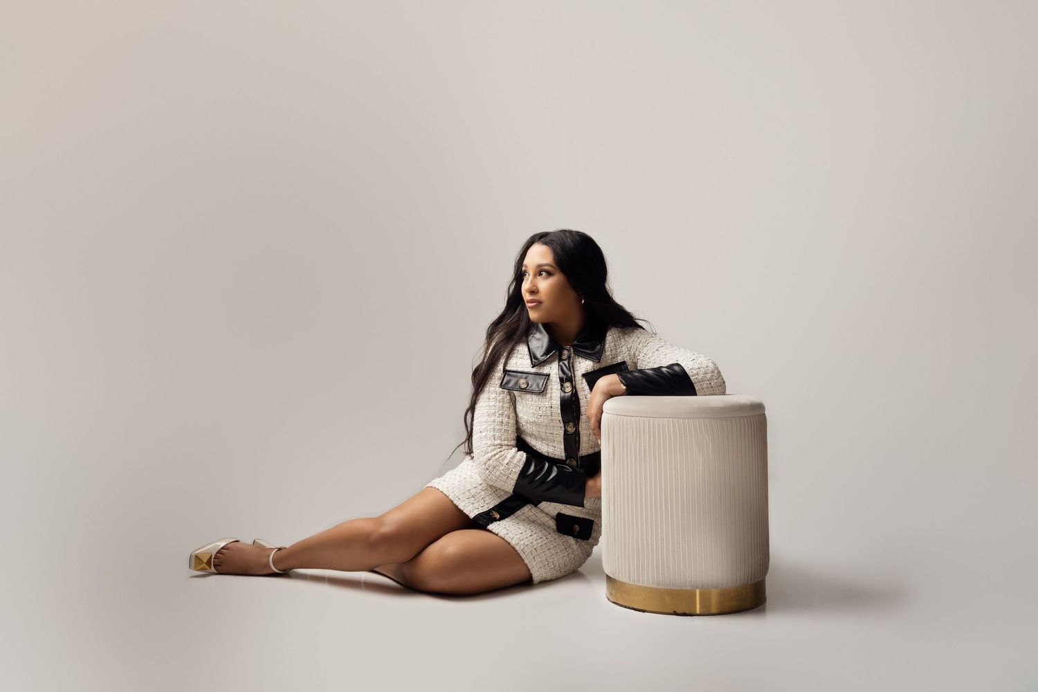 Fashion model poses in black and white outfit with chunky heels against white studio backdrop.