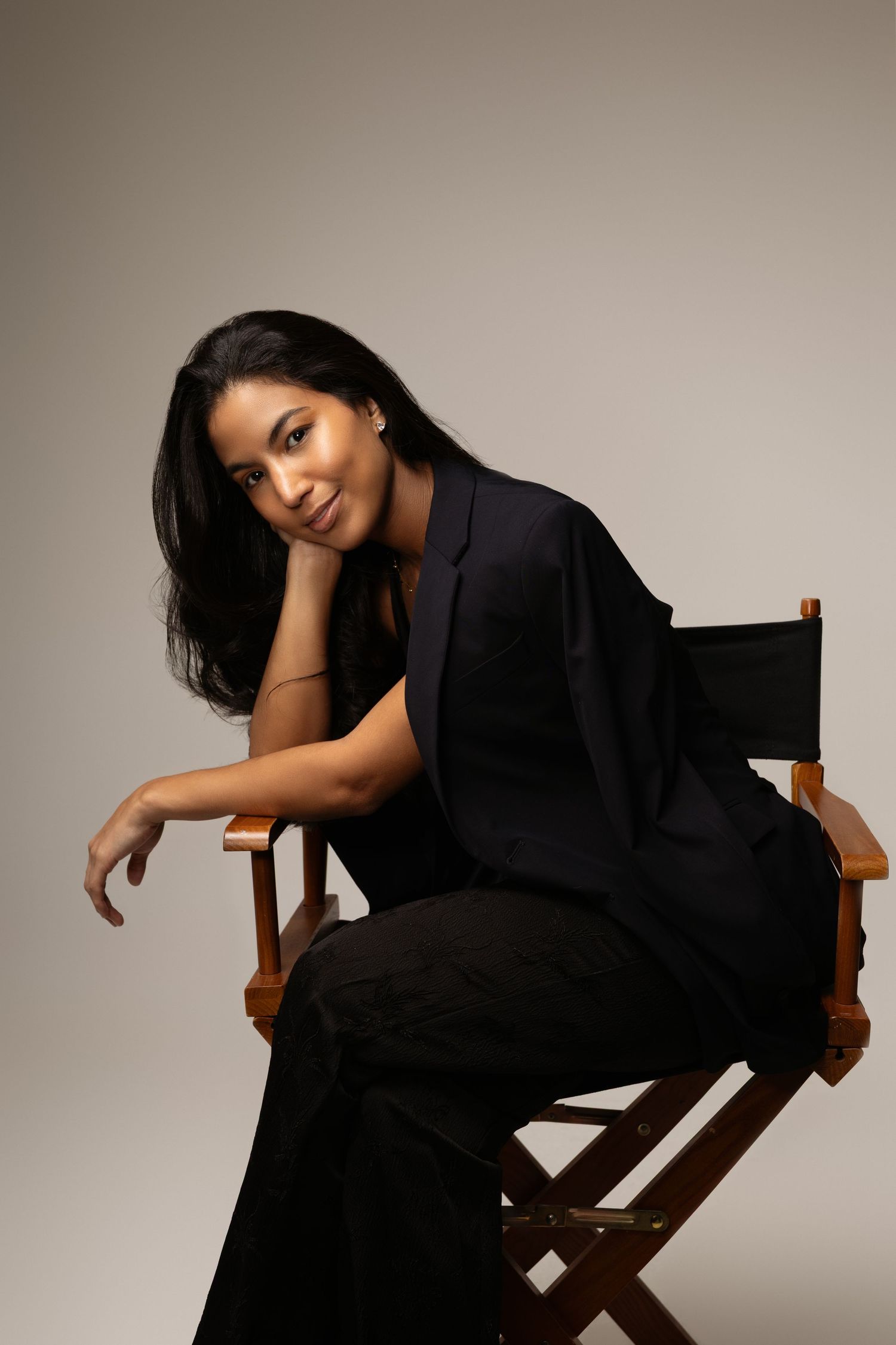 Artistic portrait series on director's chair showcasing relaxed poses in black outfit.