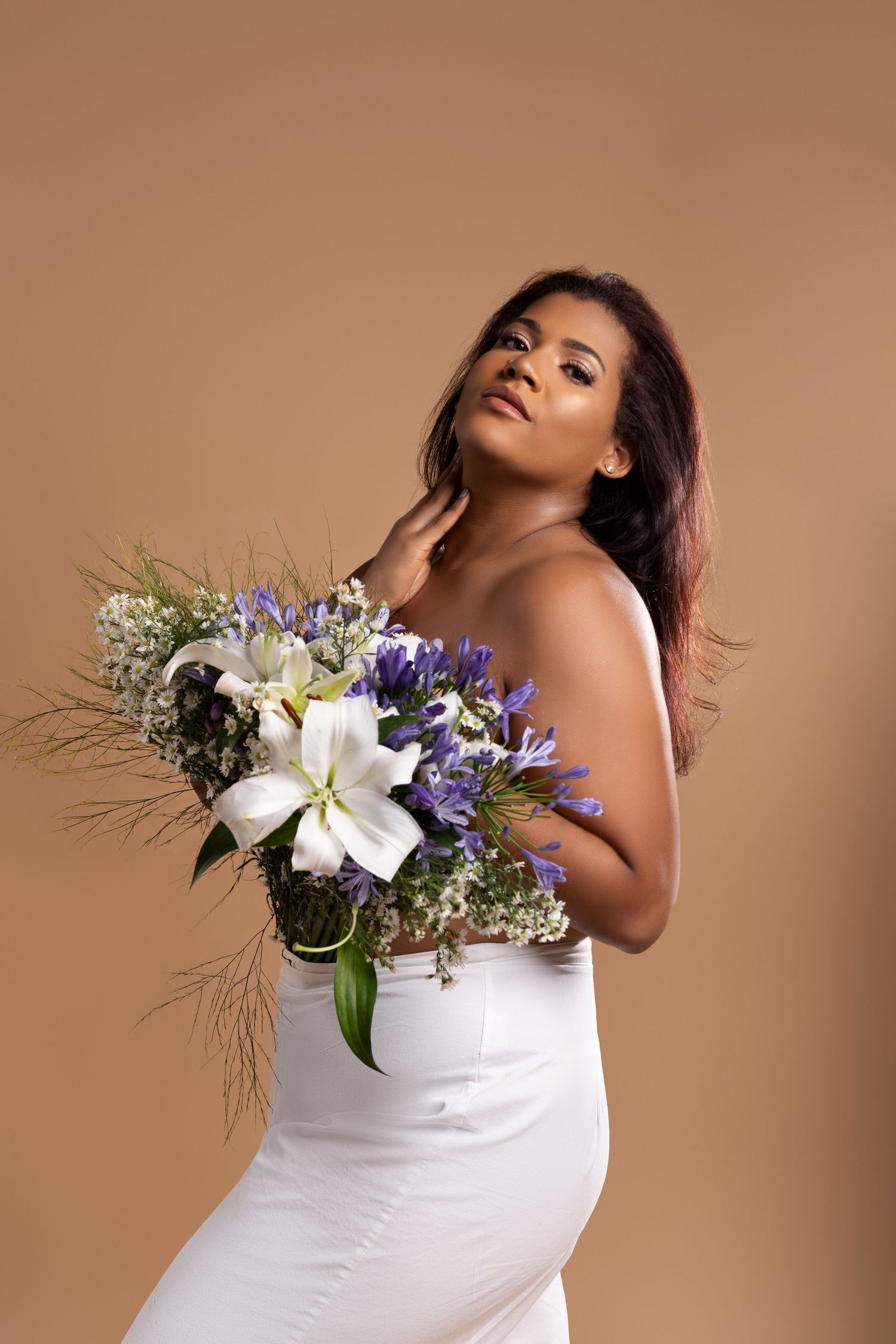 Elegant pose with white lilies and purple flowers adorning a white dress.
