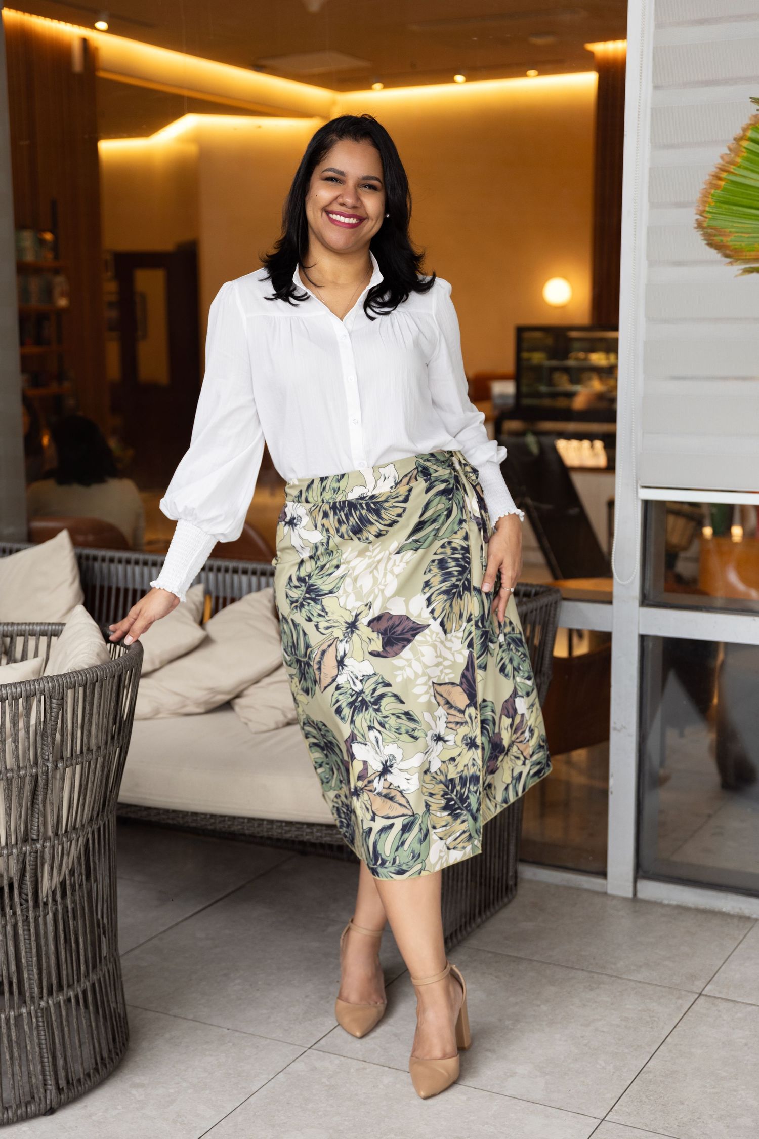 Stylish outfit with white blouse and floral skirt photographed in modern setting.