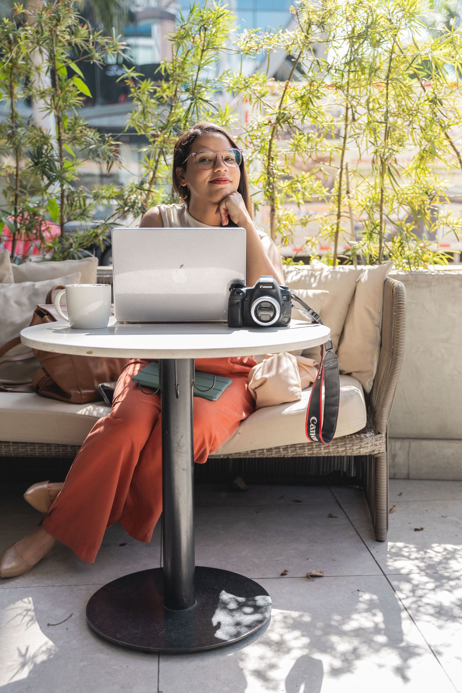 Casual outdoor cafe scene with laptop and coffee in natural sunlit setting.