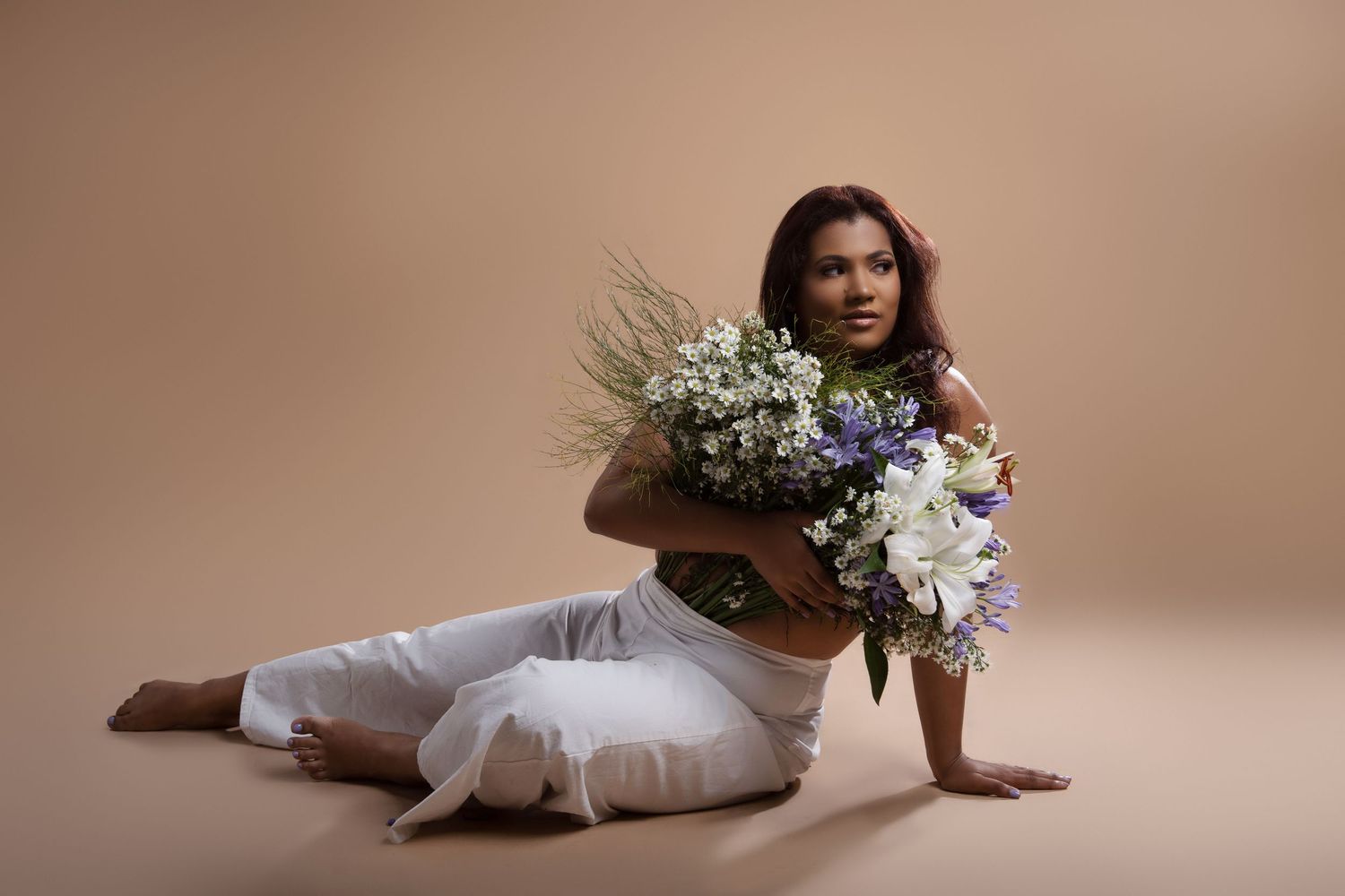 Studio photoshoot with floral elements and soft lighting on brown background.