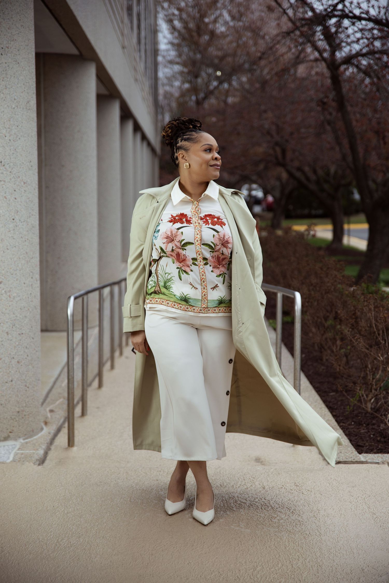 Elegant cream coat and floral dress ensemble photographed against concrete columns.