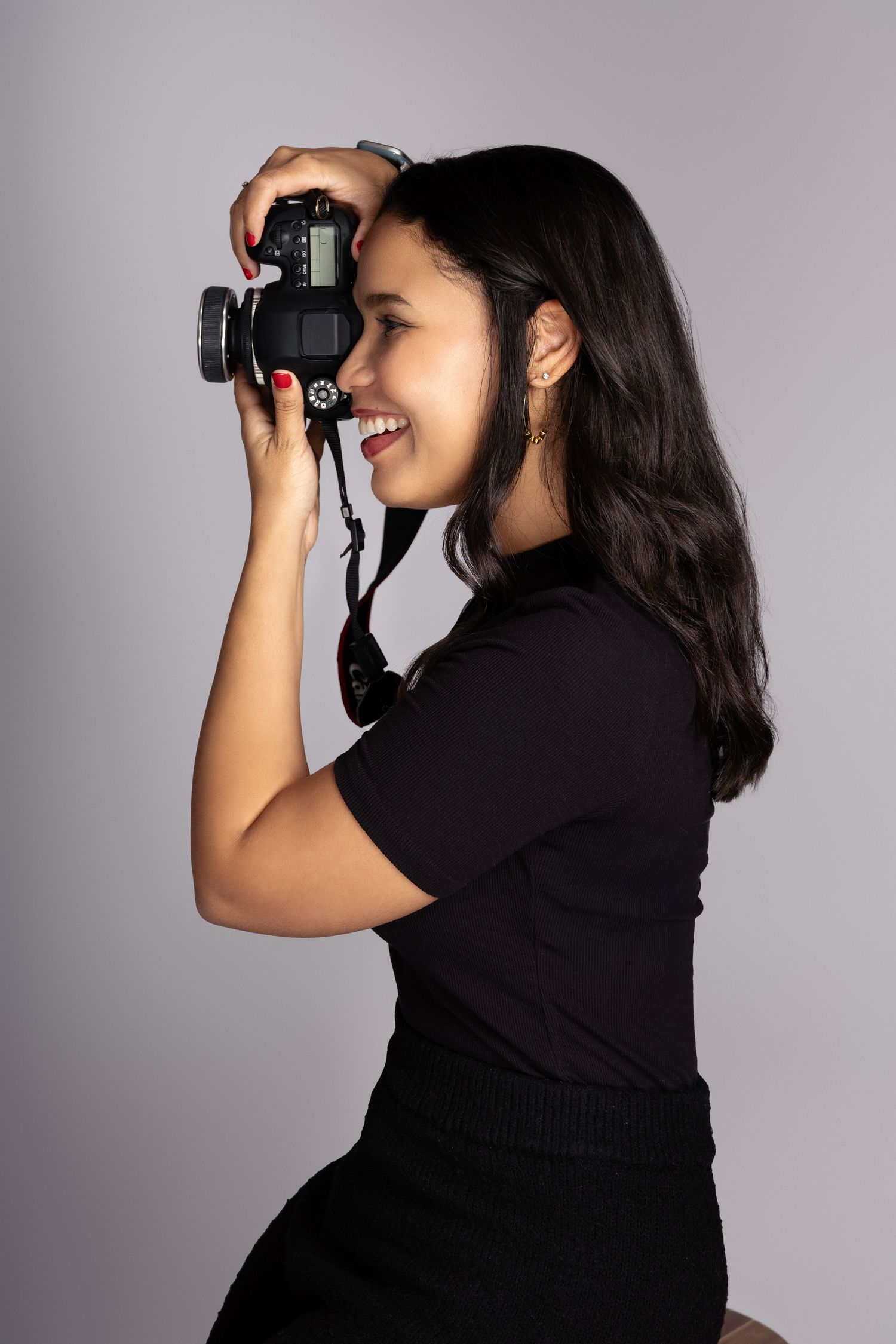Side profile of photographer in black outfit taking pictures with DSLR camera.