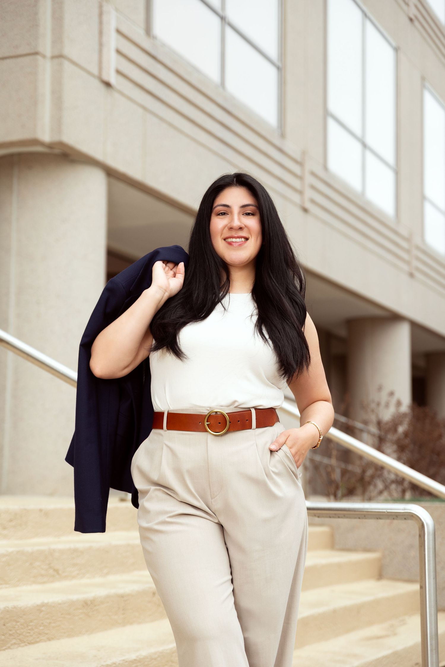 Professional fashion shoot featuring cream colored outfit with navy blazer and brown belt.