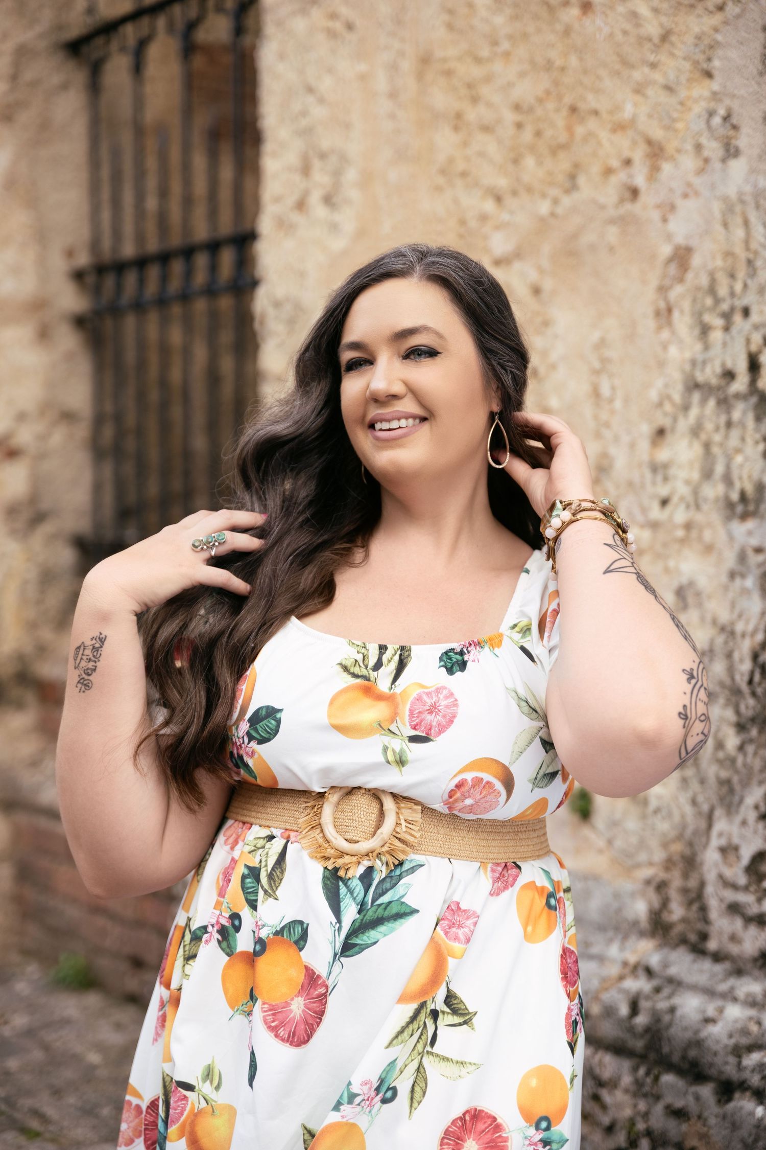 Summer fashion portrait in floral dress against textured stone wall background.