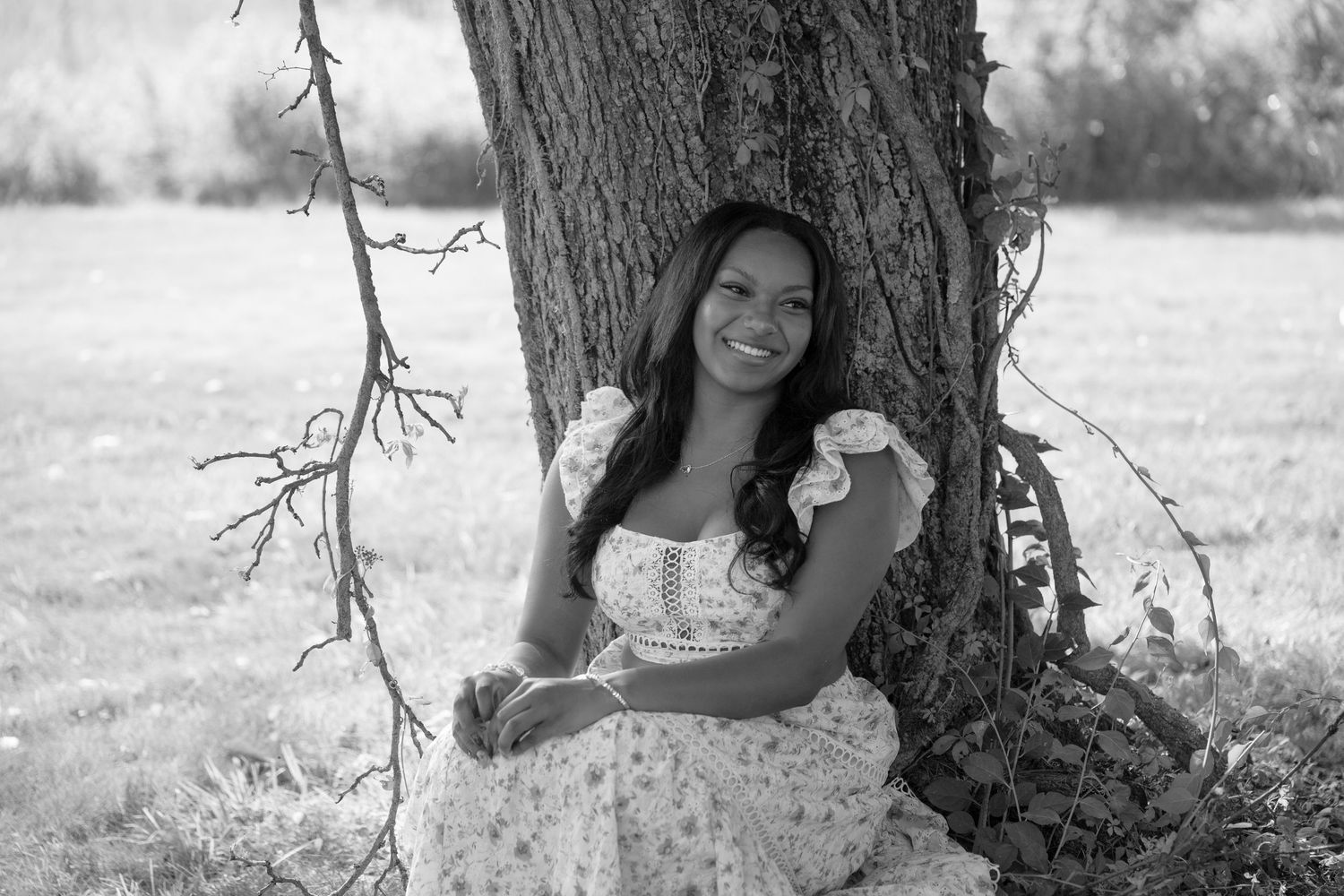Black and white artistic senior portraits taken against a large tree trunk in natural lighting.