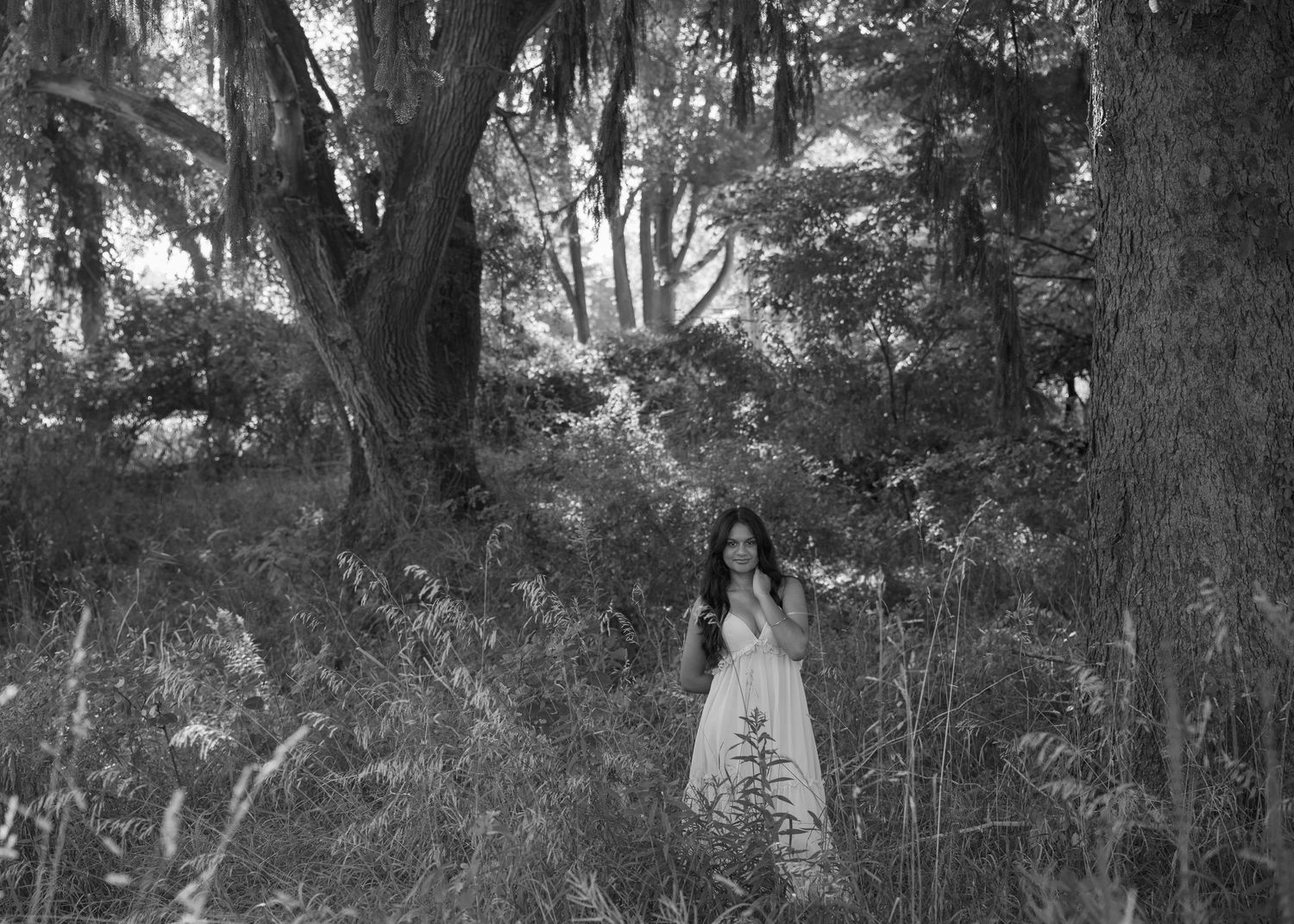 Moody black and white senior portrait session under Spanish moss draped trees creates dramatic atmosphere.