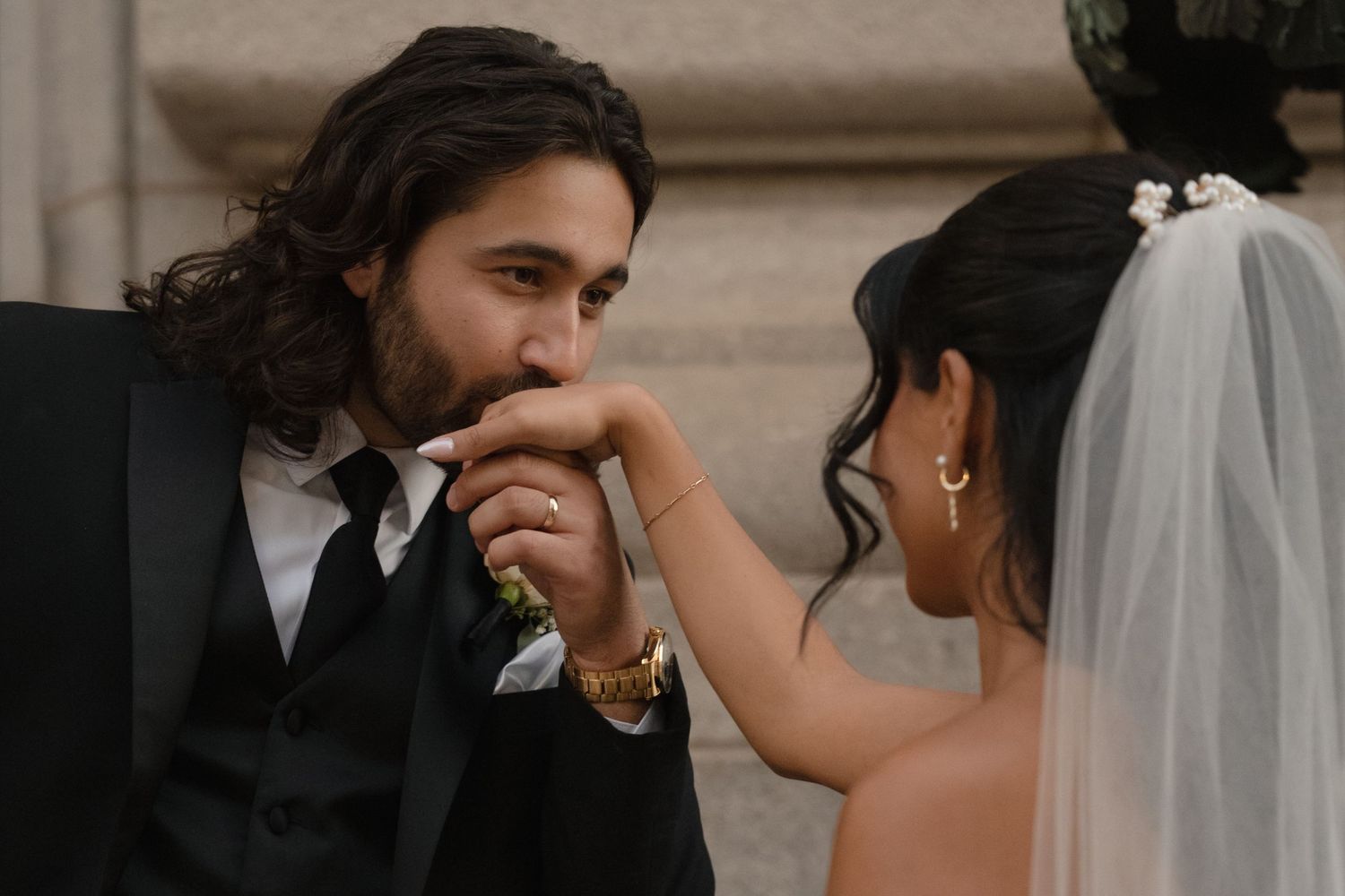An intimate wedding portrait against a stone building during golden hour.