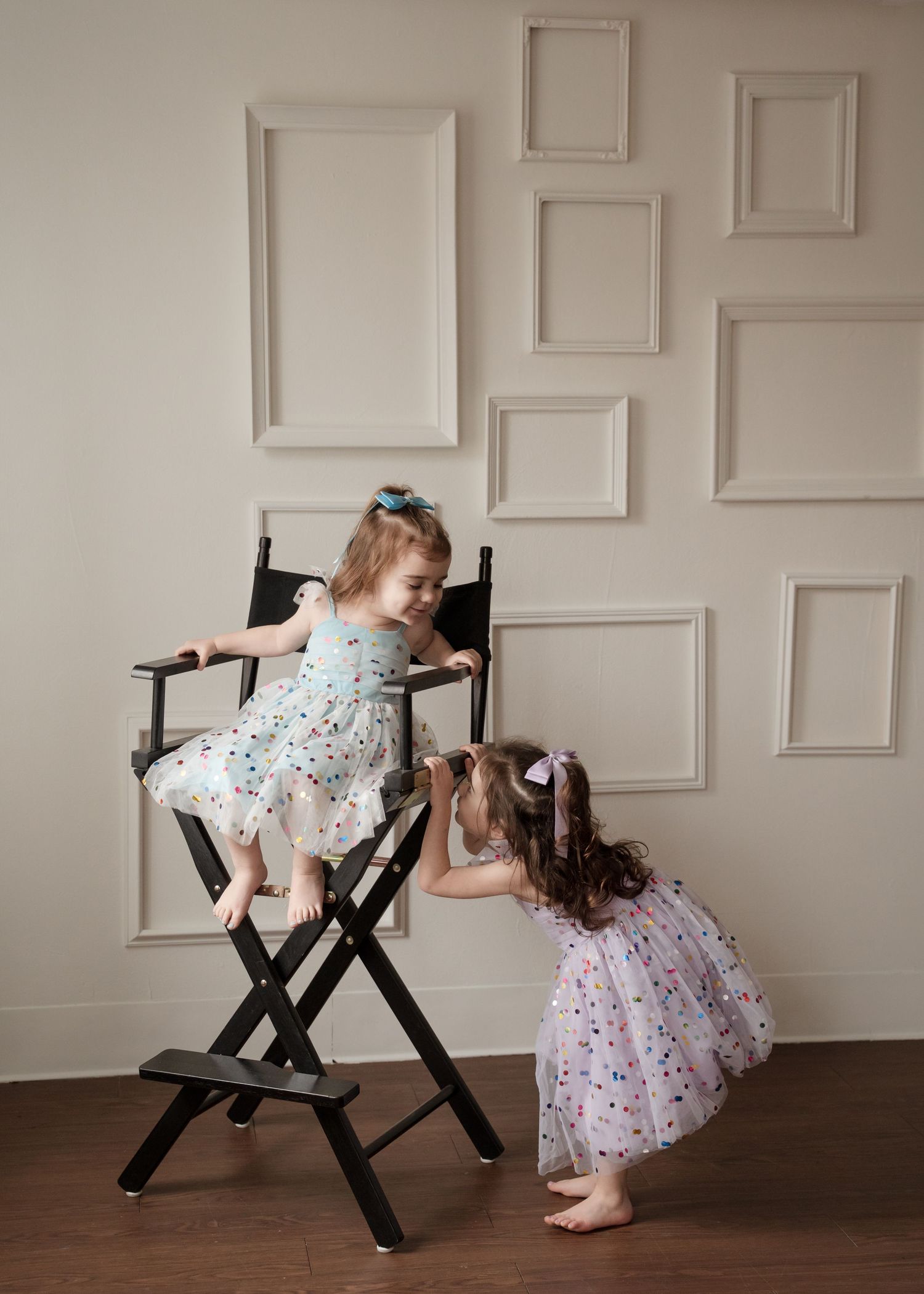 Two children in party dresses playing in studio.