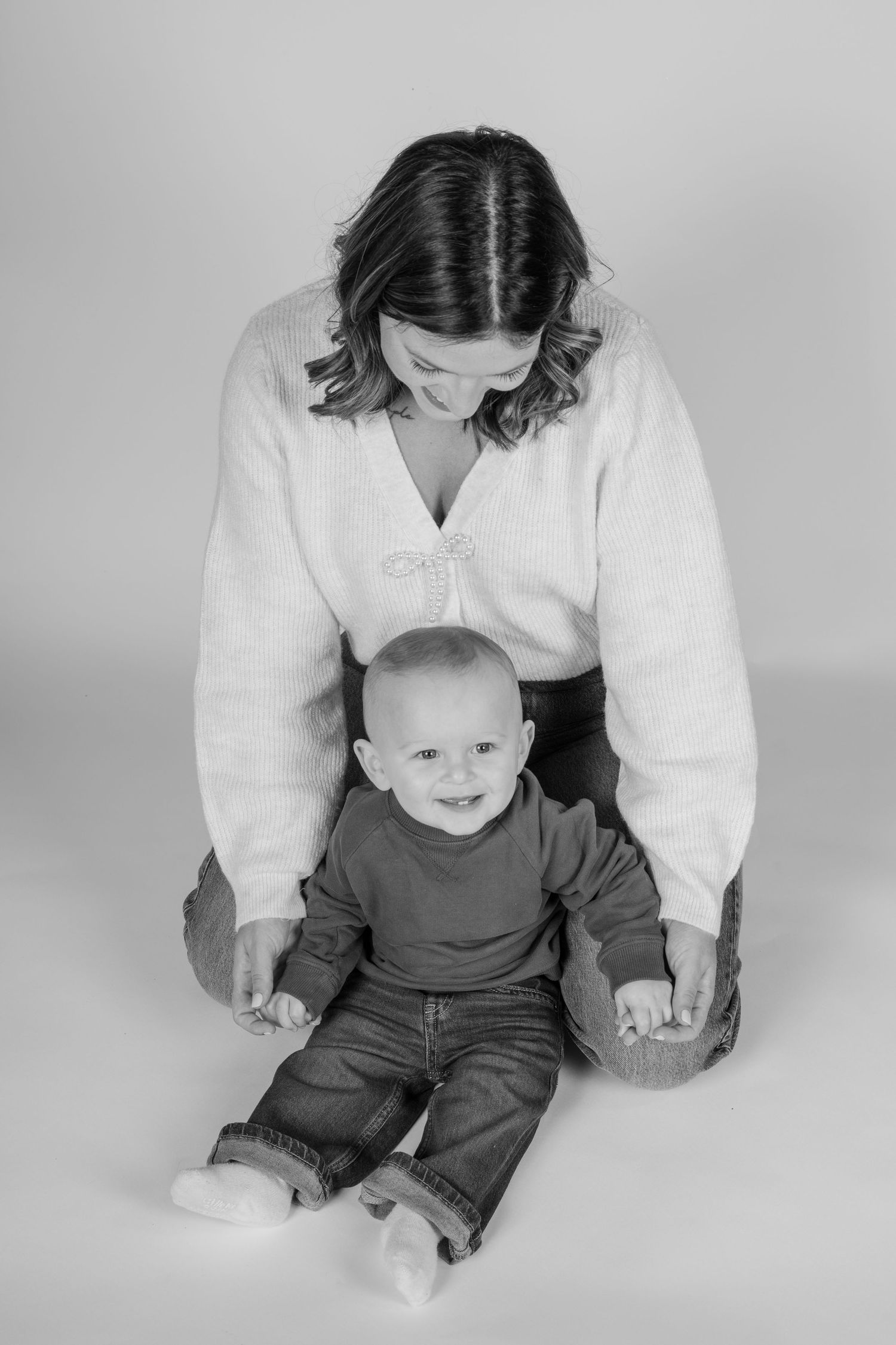 Black and white studio portrait of mom and baby in casual attire.