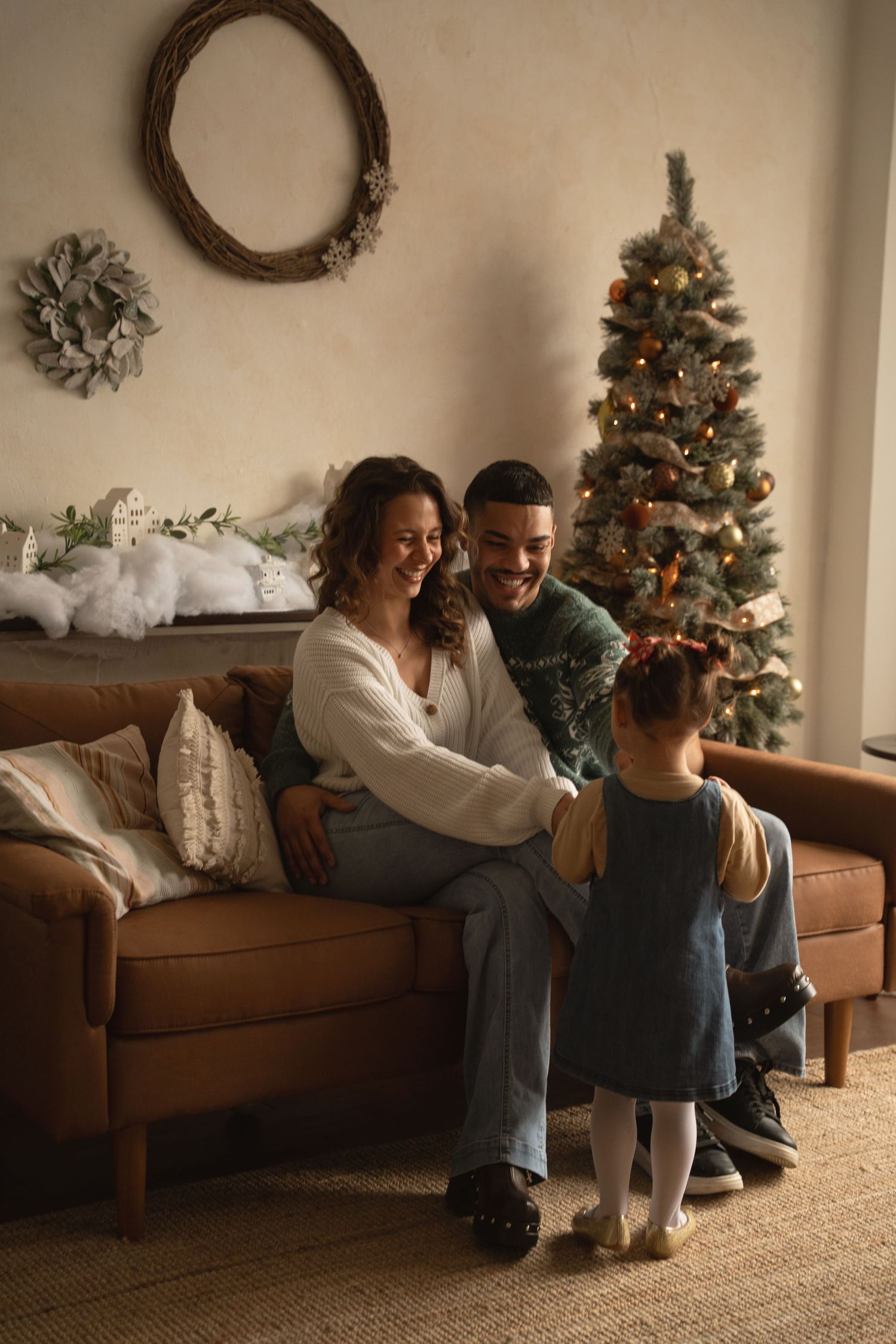 Cozy family moment on brown couch with studio decorated for Christmas in background.