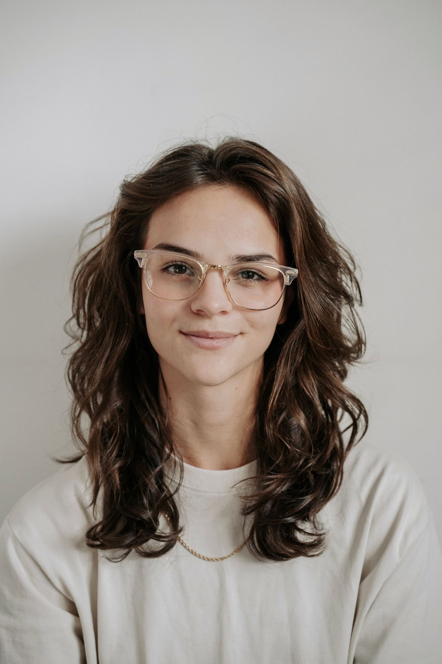 Alexa P. Artistry in studio against white background showing curly hair and glasses.