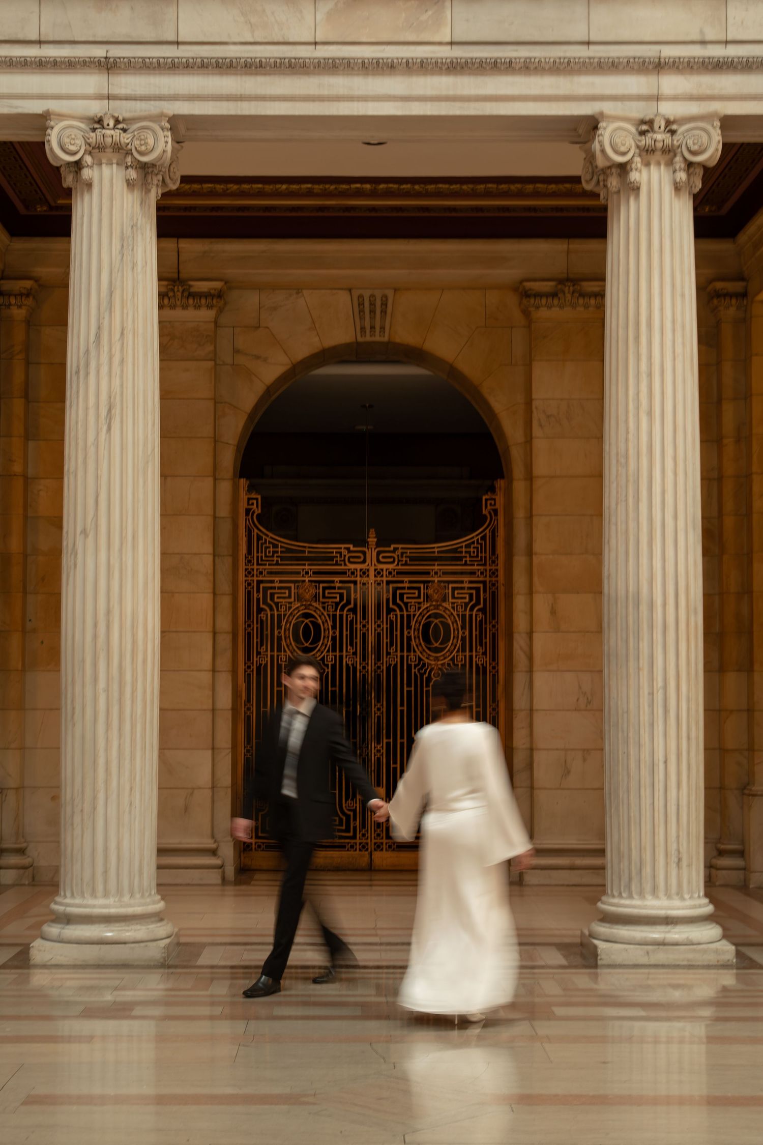 Artistic couples photo showing movement through elegant columns of a grand building.