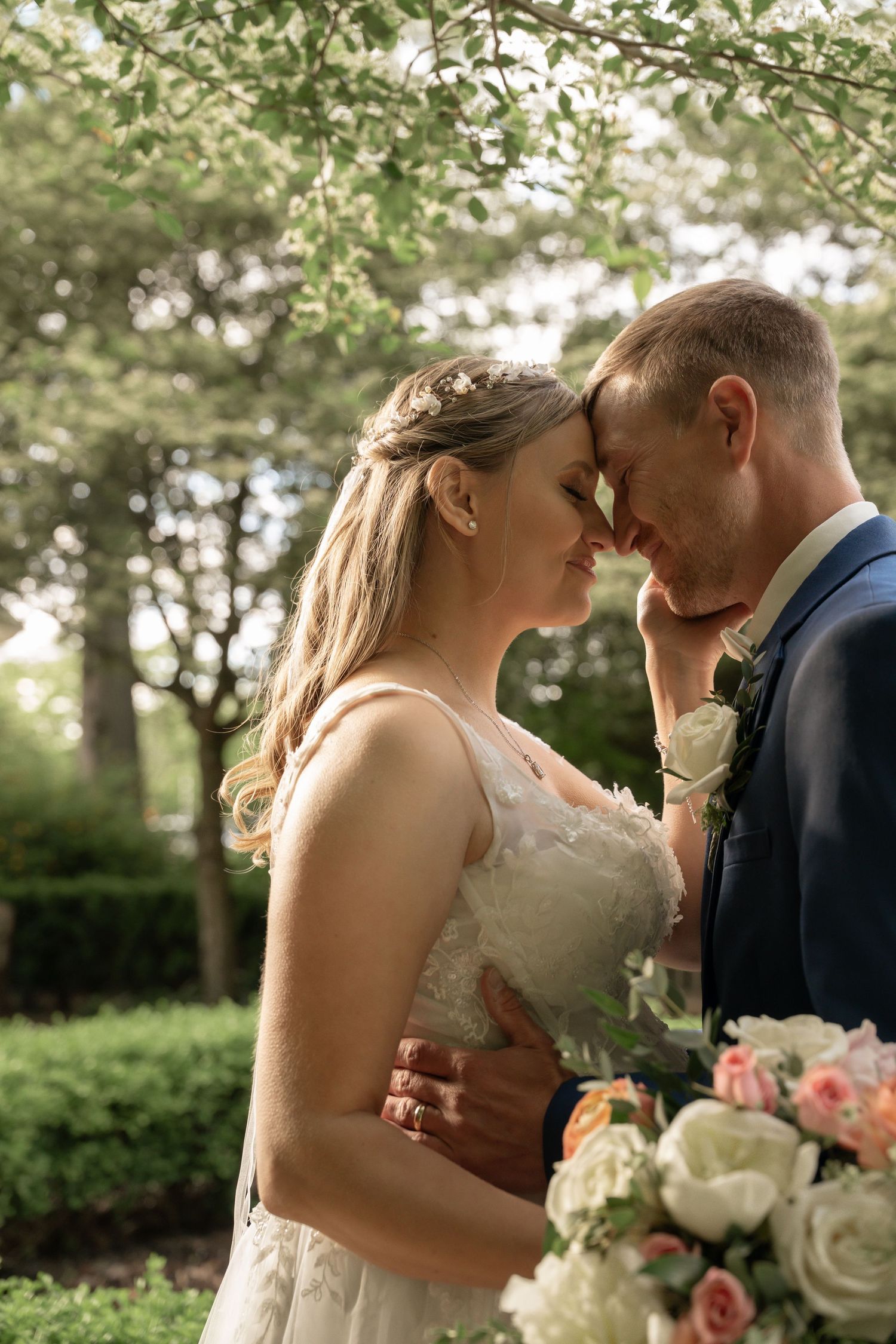 Newlyweds share intimate moment with bouquet of pink and white roses.